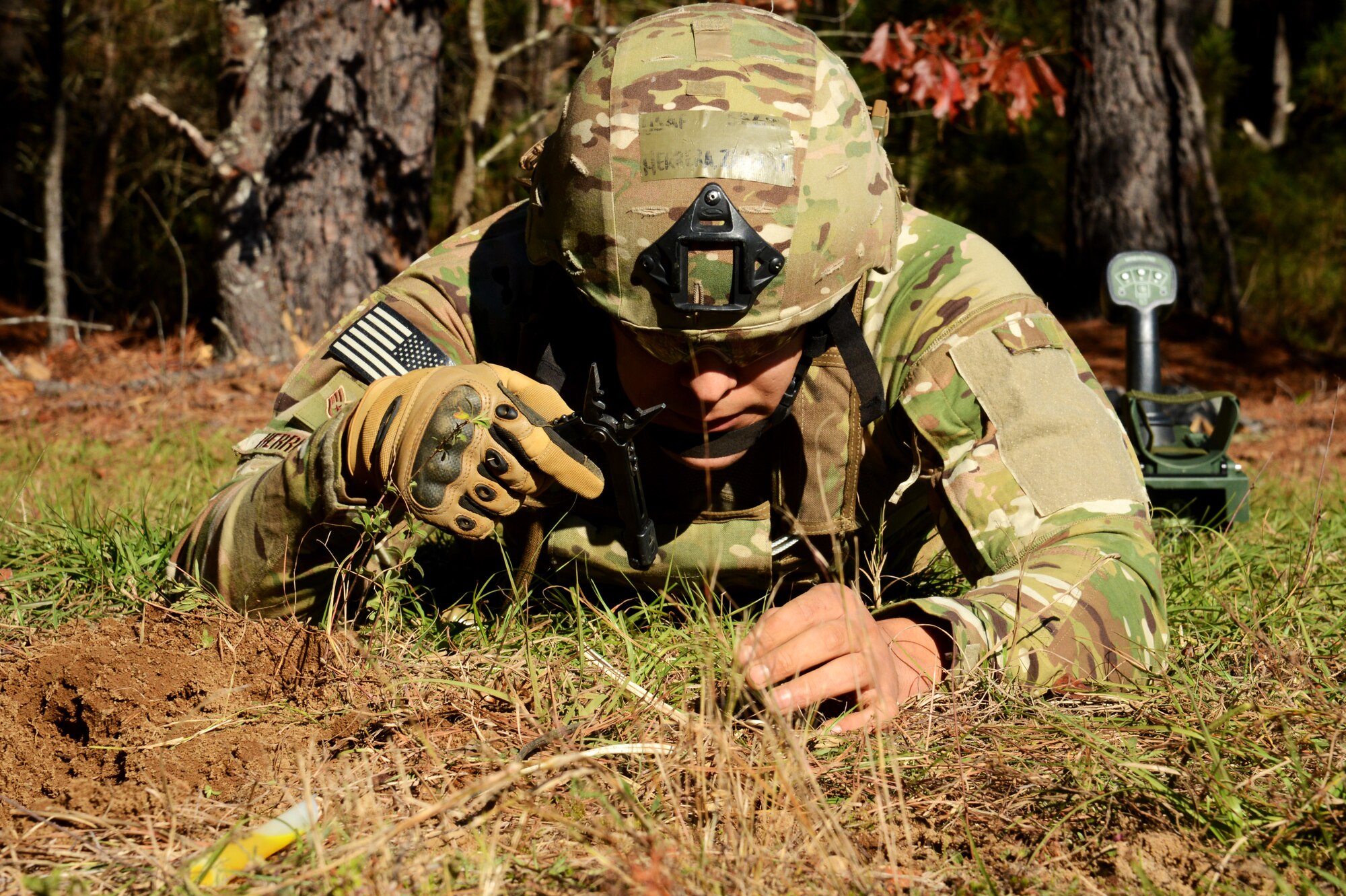 U.S. Air Force Staff Sgt. Zachary Herrera, 20th Civil Engineer Squadron Explosive Ordnance Disposal flight team leader, pulls out a multi-tool to cut a wire and diffuse an improvised explosive device (IED) during the EOD flight’s working demonstration at Shaw Air Force Base, S.C., Dec. 4, 2015. Herrera and his teammate swept a section of trail on base to simulate EOD working procedures. Upon finding a simulated IED, Herrera worked close to the ground in a prone position to limit his exposure should the IED explode. (U.S. Air Force photo by Senior Airman Jonathan Bass)