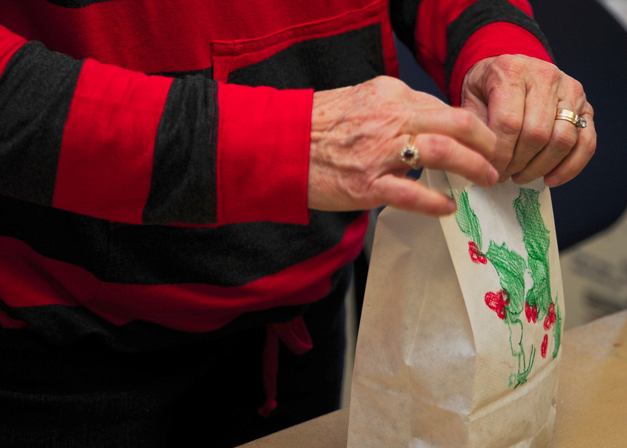 Bonnie Else, wife of a retired U.S. Airman, staples ribbons to decorated paper bags at the annual Cookie Crunch at Davis-Monthan Air Force Base, Ariz., Dec. 7, 2015. Each paper bag was counted and placed into boxes labeled for pick-up and distribution. (U.S. Air Force photo by Airman 1st Class Ashley N. Steffen/Released)