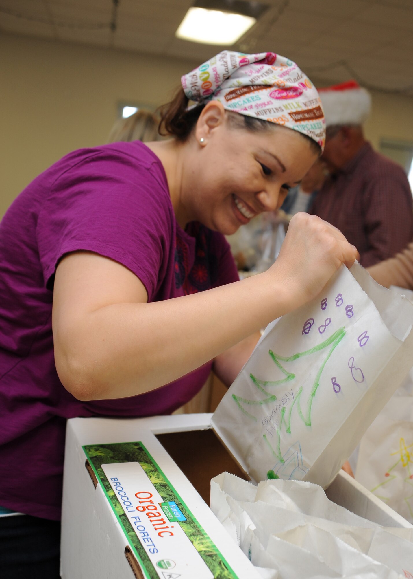 Jennifer Thompson, wife of U.S. Air Force Lt. Col. James Thompson, 355th Dental Squadron director of operations and deputy commander, places a bag of cookies into a distribution box during the annual Cookie Crunch at Davis-Monthan Air Force Base, Ariz., Dec. 7, 2015. After the cookies were placed into boxes, squadron first sergeants distributed the cookies to Airmen living in the base dorms.  (U.S. Air Force photo by Airman 1st Class Ashley N. Steffen/Released)