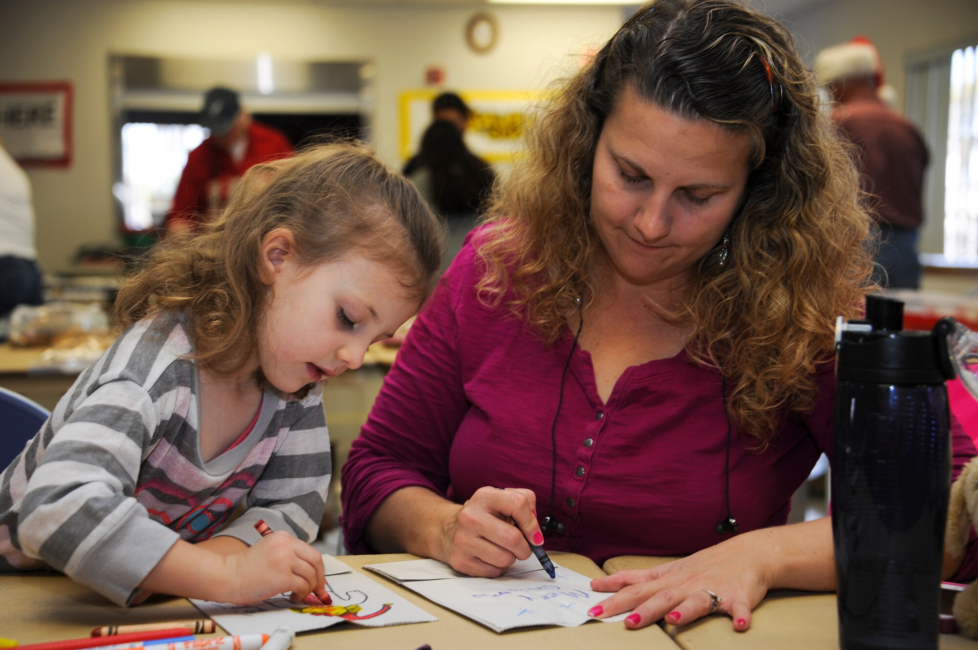 Cheryl Jobe, wife of U.S. Air Force Capt. Michael Jobe, 355th Medical Operations Suqadron orthopedic physcians assistant, and their daughter draw on bags during the annual Cookie Crunch at Davis-Monthan Air Force Base, Ariz., Dec. 7, 2015. Bags were decorated by the School Age and Youth Programs, Ventana Vista and Cienega High School Key Clubs and other volunteers on base. (U.S. Air Force photo by Airman 1st Class Ashley N. Steffen/Released)