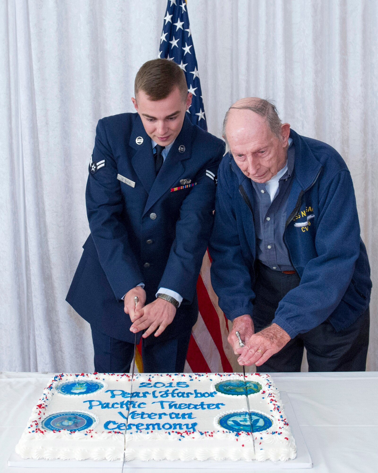 Airman 1st Class Montana Beckham, an Airman with the Air Force Technical Applications Center, and Clarence Bud Lane, a Pearl Harbor survivor, cut the cake with ceremonial swords during the 20th Annual Pearl Harbor and Pacific Theater Veteran Ceremony Dec. 7, 2015.  The event was sponsored by the treaty monitoring center to honor and pay tribute to those who served in the Pacific Theater.  (U.S. Air Force photo by Matthew Jurgens)