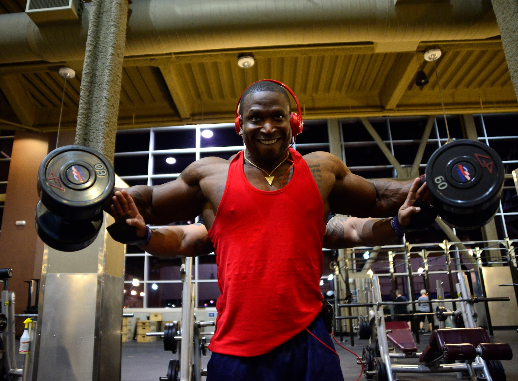 Tech. Sgt. David, 432nd Maintenance Group contract officer representative, performs lateral raises while his trainer, Derrick Chandler, motivates him during a workout Dec. 4, 2015, at Nellis Air Force Base, Nevada. David recently attained his International Federation of Bodybuilding and Fitness professional card which allows him to compete in professional bodybuilding competitions. (U.S. Air Force photo by Airman 1st Class Christian Clausen/Released)