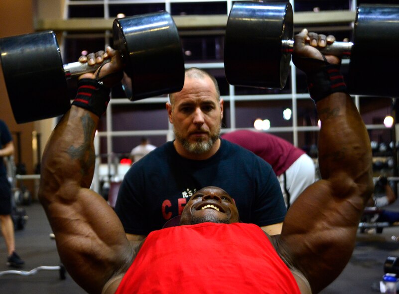 Tech. Sgt. David, 432nd Maintenance Group contract officer representative, performs chest fly's  while his trainer, Derrick Chandler, motivates him during a workout Dec. 4, 2015, at Nellis Air Force Base, Nevada. David recently attained his International Federation of Bodybuilding and Fitness professional card which allows him to compete in professional bodybuilding competitions. (U.S. Air Force photo by Airman 1st Class Christian Clausen/Released)