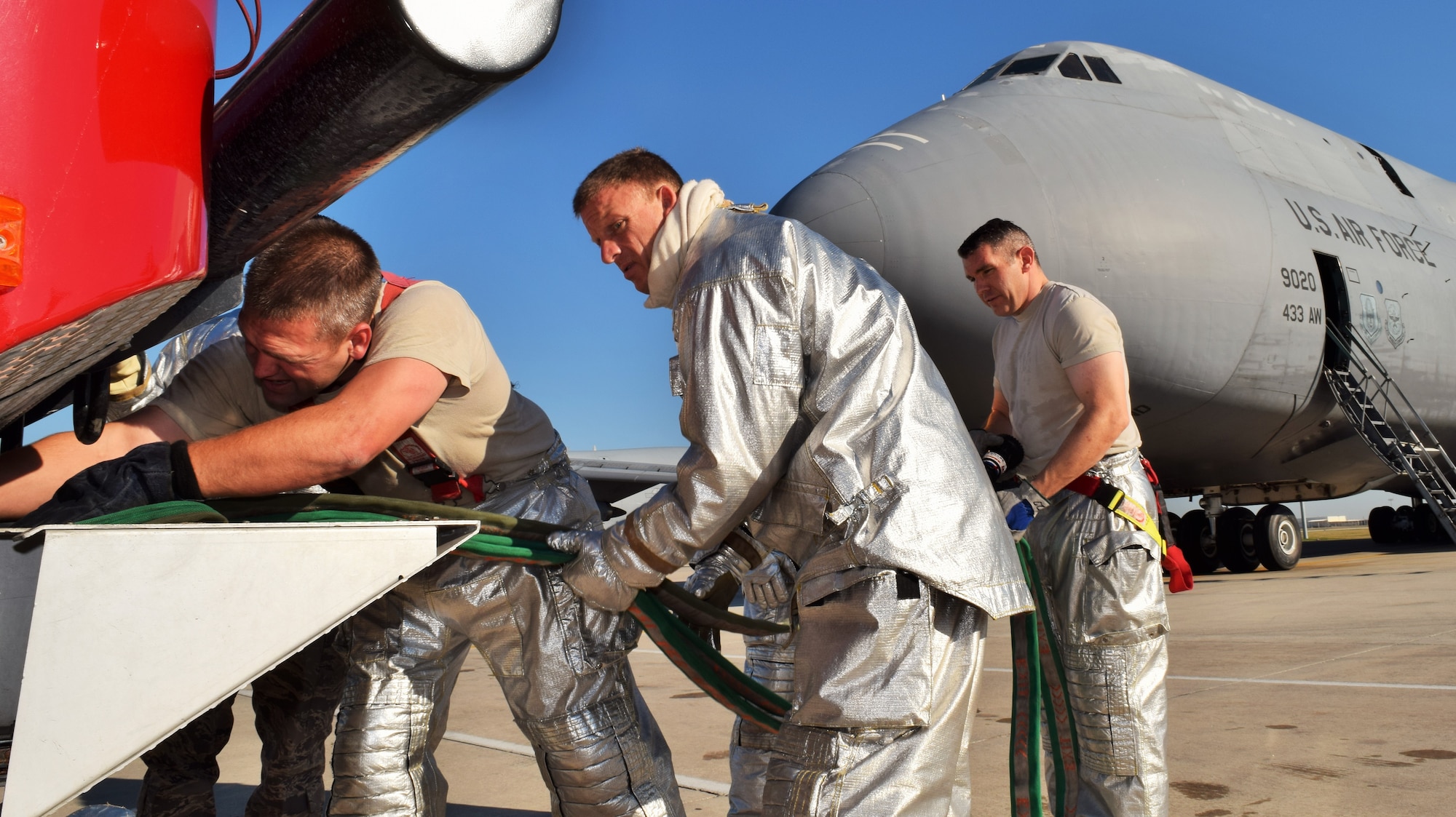 (From left to right) Tech. Sgt. Stephen Johnson, Staff Sgt. Aaron Best, and Senior Airman Iain Thompson, 433rd Civil Engineer Squadron firefighters, work together to store a hose in a fire truck at the end of a C-5 egress training exercise Dec. 6, 2015 on the Joint Base San Antonio-Lackland flightline. The C-5 egress training is an annual requirement for the firefighters who were evaluated on their response procedures, ability to extinguish the fire, conduct search and rescue and shut off the aircraft.  (U.S. Air Force photo/Tech. Sgt. Lindsey Maurice)