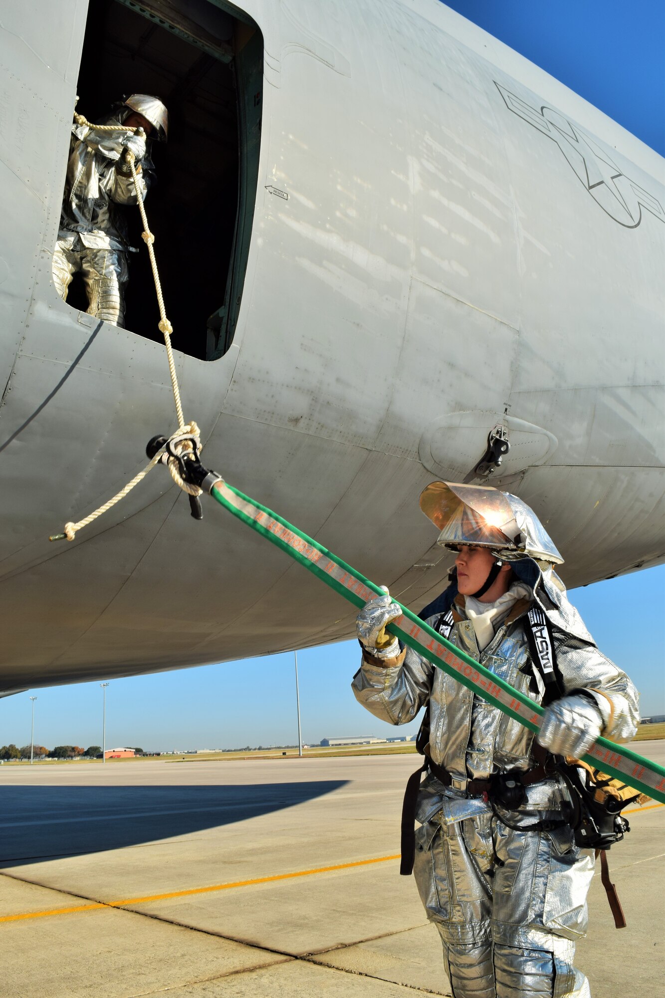 Tech. Sgt. Nicola Marler, 433rd Civil Engineer Squadron firefighters, sends a hose line up through the back of a C-5A Galaxy as part of an annual training exercise Dec. 6, 2015 on the Joint Base San Antonio-Lackland flightline. The C-5 egress training is an annual requirement for the firefighters who were evaluated on their response procedures, ability to extinguish the fire, conduct search and rescue and shut off the aircraft.  (U.S. Air Force photo/Tech. Sgt. Lindsey Maurice)