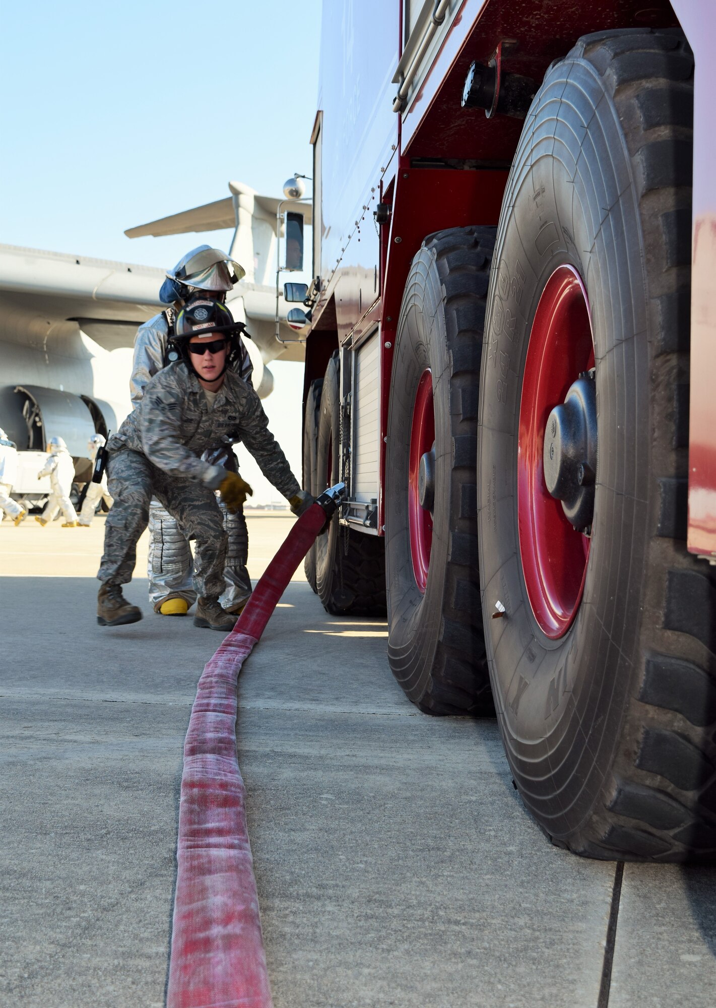 Senior Airman Shannon Seay, 433rd Civil Engineer Squadron firefighter, readies a hose for fellow firefighters before simulating extinguishing a C-5A Galaxy engine fire Dec. 6, 2015 on the Joint Base San Antonio-Lackland, Texas flightline. The firefighters are required to conduct C-5 egress training annually in order to remain proficient. The scenario required the team to respond to number one and number two engine fires on the aircraft. In addition to extinguishing the fire, the team had to shut the aircraft off and conduct a search and rescue sweep.  (U.S. Air Force photo/Tech. Sgt. Lindsey Maurice)