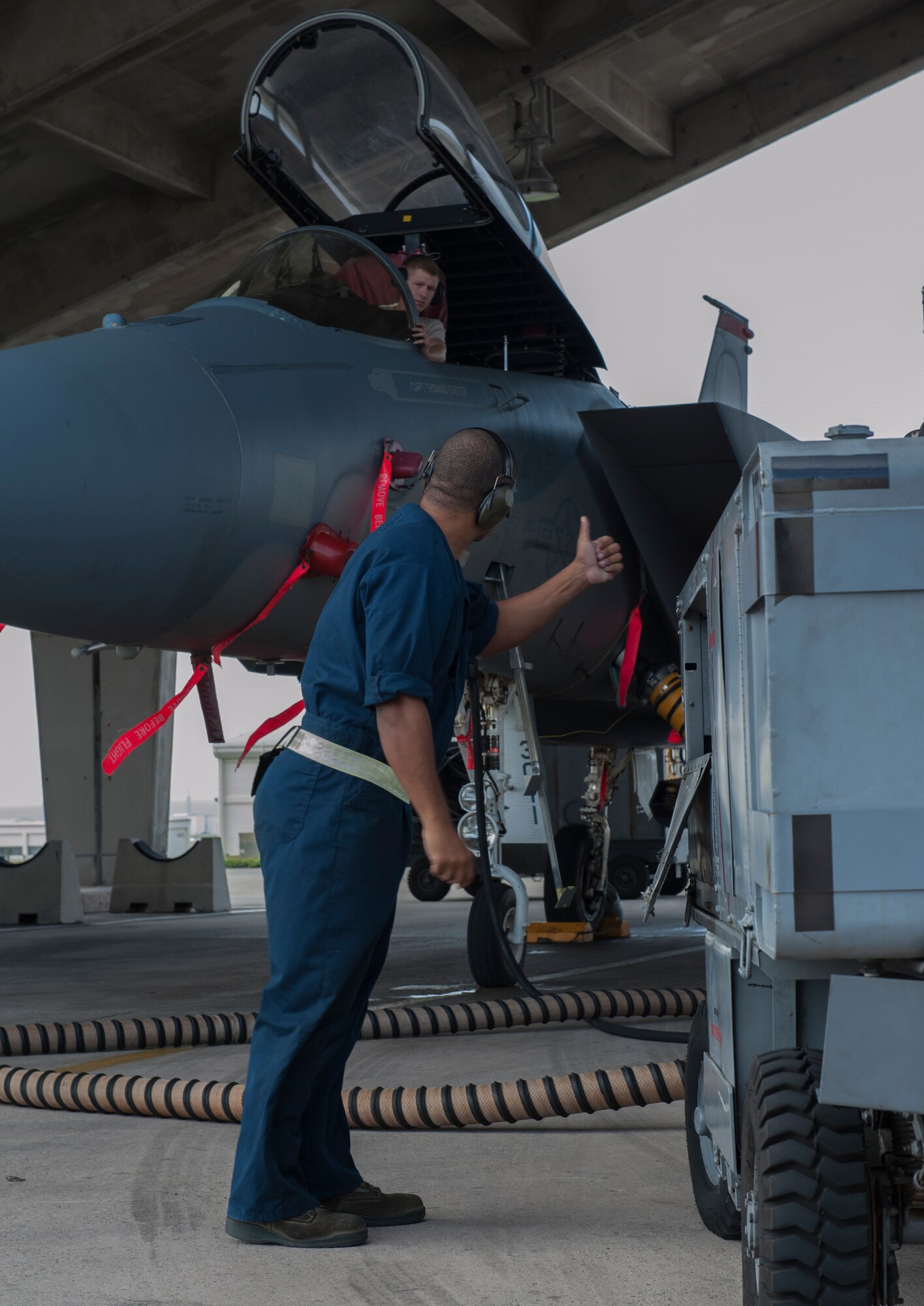 U.S. Air Force Airman 1st Class Brandon Martel, 67th Aircraft Maintenance Unit avionics technician apprentice, signals to Senior Airman Adam Craig, 67th AMU avionics technician journeyman, that the power cart, used to supply power to the F15C Eagle during maintenance, is operating correctly, Dec. 8, 2015, at Kadena Air Base, Japan. Teamwork is a vital part of the operational checks the 67th AMU completes daily. (U.S. Air Force photo by Airman Zackary A. Henry)