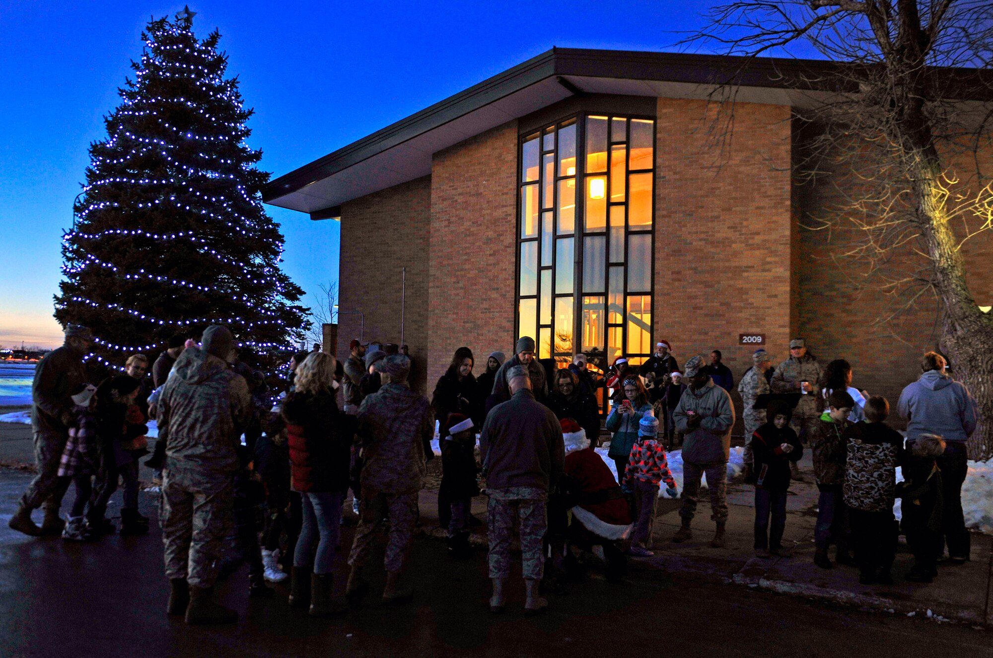 Families gather in front of the Freedom Chapel during the 28th Bomb Wing tree lighting ceremony at Ellsworth Air Force Base, S.D., Dec. 2, 2015, for group Christmas carols, the lighting of the tree and a surprise visit from Santa. (U.S. Air Force photo by Airman 1st Class James L. Miller/Released)