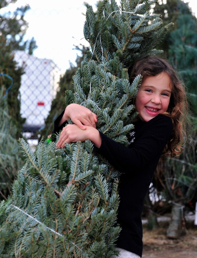 Nikia Hunter, daughter of Bryan Hunter, tree recipient, embraces the Christmas tree she picked out during Trees for Troops at Ellsworth Air Force Base, S.D., Dec. 4, 2015. Hunter and her family received the tree at no cost and had volunteers assist in loading it into their vehicle. (U.S. Air Force photo by Airman 1st Class James L. Miller/Released)