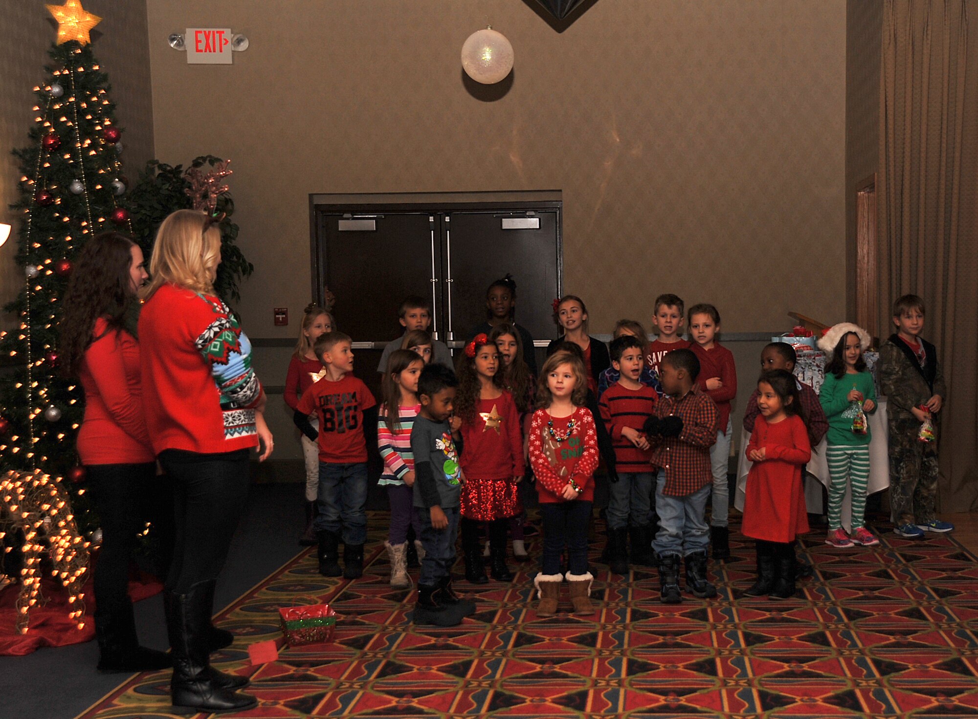 Children sing carols at the Holiday Tree Lighting ceremony in the Northern Lights Club on Grand Forks Air Force Base, North Dakota, Dec. 7, 2015. Additional activities at the event included a visit from Santa Claus, ornament making and free hot chocolate. (U.S. Air Force photo by Senior Airman Bonnie Grantham/released)