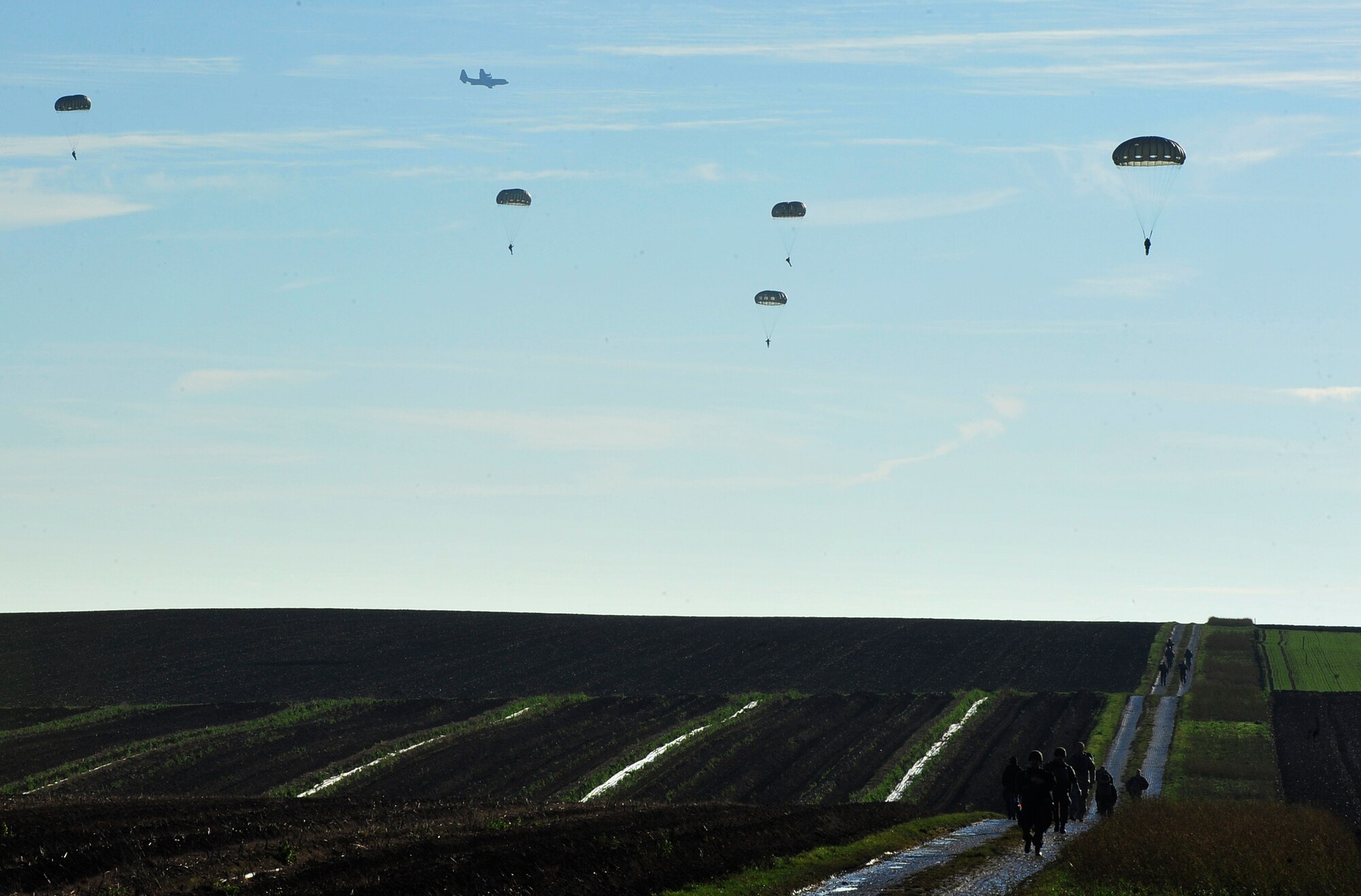 Airmen, Soldiers, NATO members and Santa Claus parachute onto a landing zone during an International Jump Week toy drop event Dec. 7, 2015, at Alzey Drop Zone, Germany. International Jump Week is an event that gives NATO members the opportunity to work together and build camaraderie and partnerships. (U.S. Air Force photo/Airman 1st Class Larissa Greatwood)