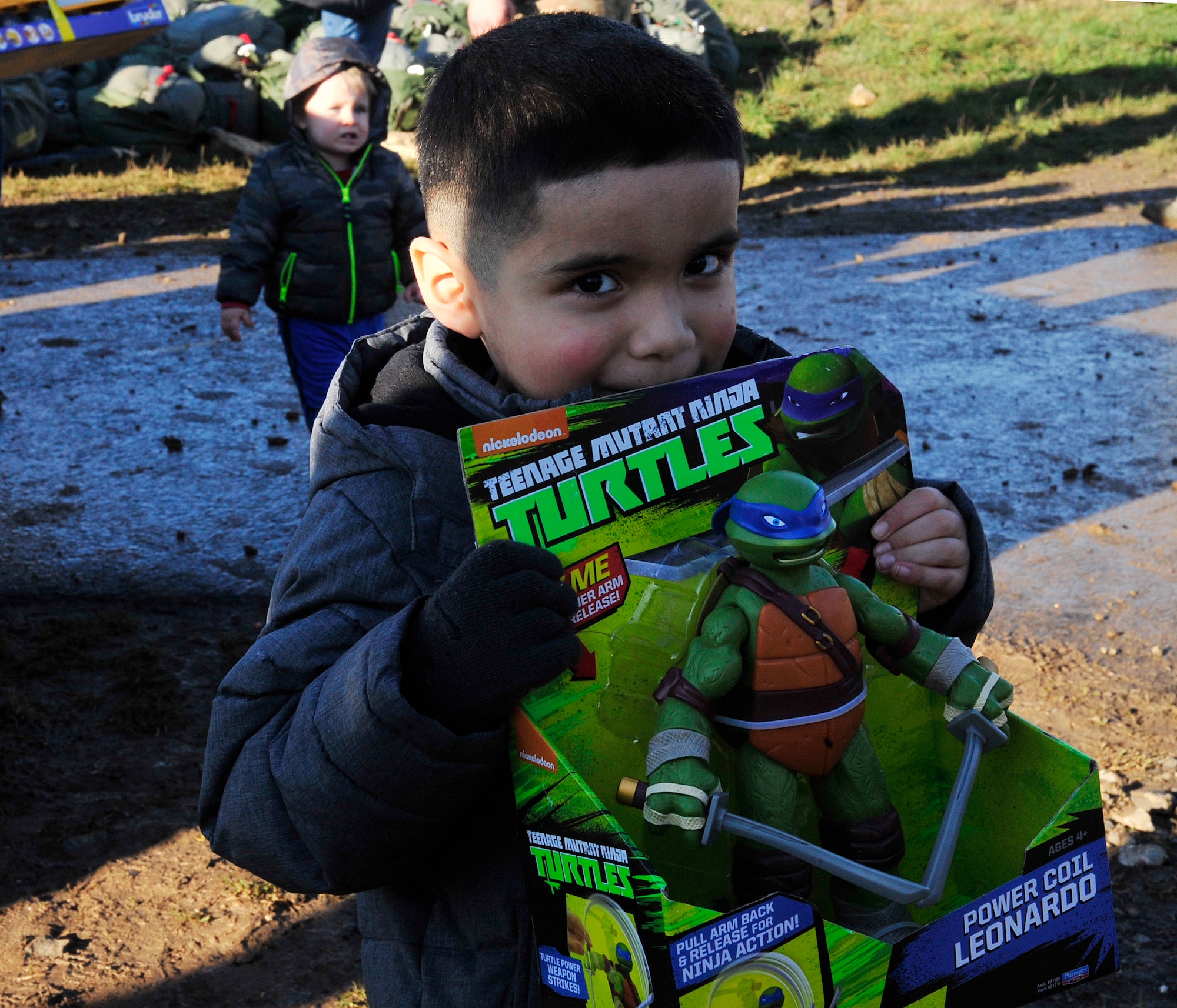Julian Obregon, son of Tech. Sgt. Jose Obregon, 435th Contingency Response Group independent duty medical technician, shows off his toy from Santa Claus during the International Jump Week toy drop Dec. 7, 2015, at Alzey Drop Zone, Germany. The toy drop is a yearly event in which toys are dropped to children in the community during the holiday season. (U.S. Air Force photo/Airman 1st Class Larissa Greatwood)