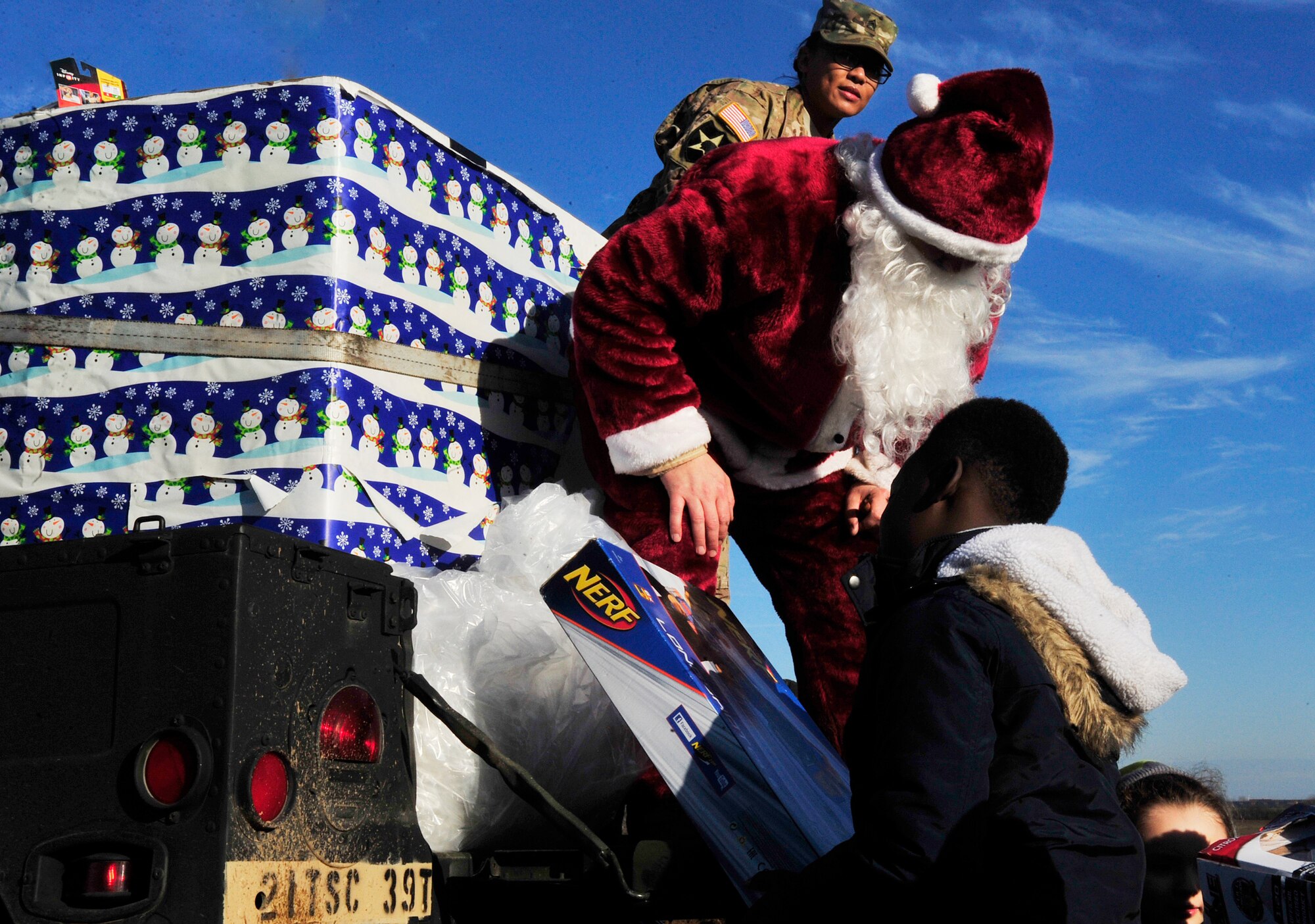 Santa Claus hands a child a toy during toy drop, which initiated International Jump Week, Dec. 7, 2015, at Alzey Drop Zone, Germany. Families watched as paratroopers jumped from a C-130J Super Hercules and received gifts from Santa to kick off the holiday season. (U.S. Air Force photo/Airman 1st Class Larissa Greatwood)