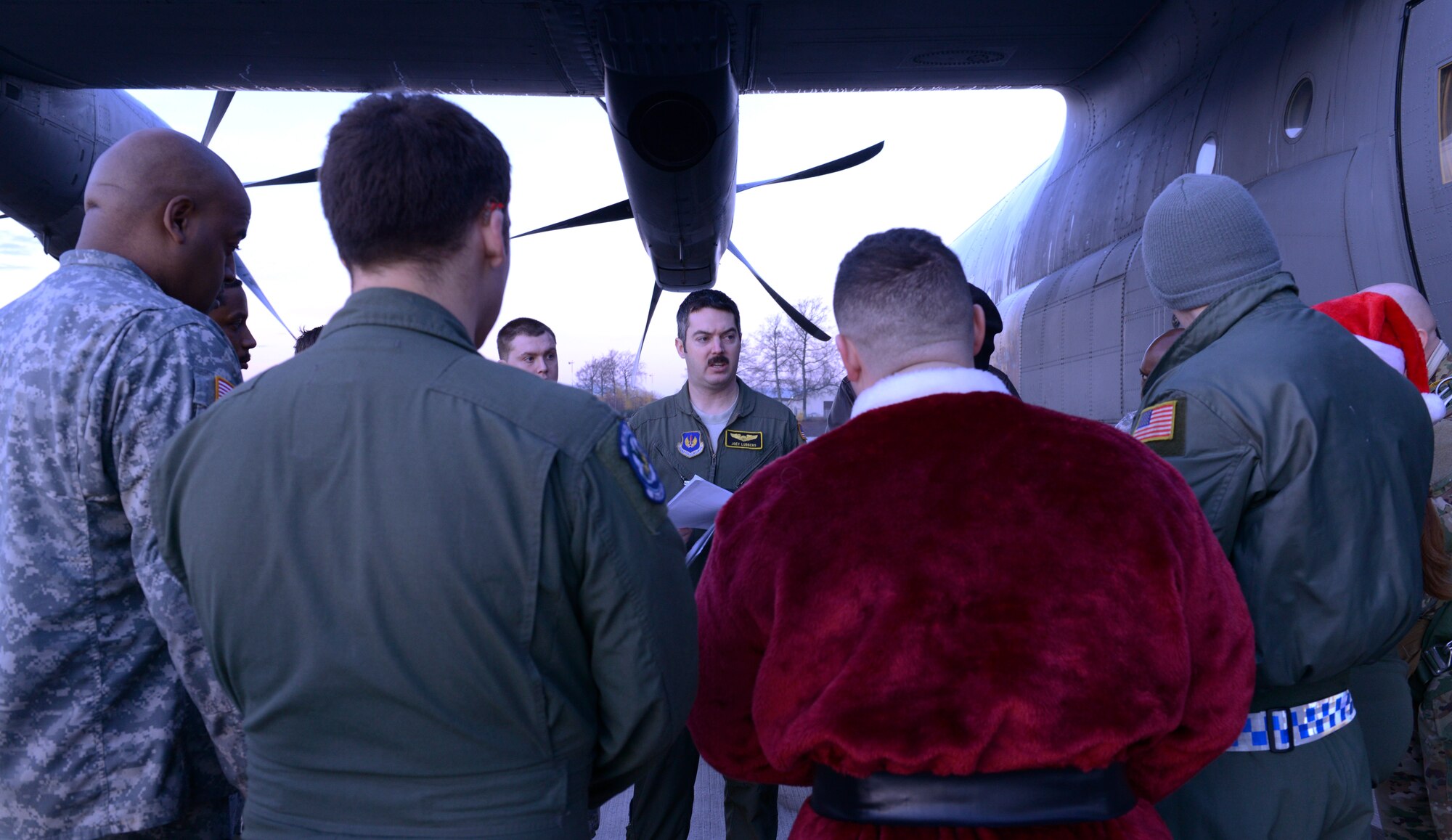 Airmen, Soldiers, NATO members and Santa Claus listen to a brief before parachuting out of a C-130J Super Hercules for an International Jump Week toy drop event Dec. 7, 2015, at Ramstein Air Base, Germany. The paratroopers, along with a pallet of toys, were dropped at the Alzey Drop Zone, Germany. International Jump Week is an event that gives NATO members the opportunity to work together and build camaraderie and partnerships. (U.S. Air Force photo/Airman 1st Class Tryphena Mayhugh)