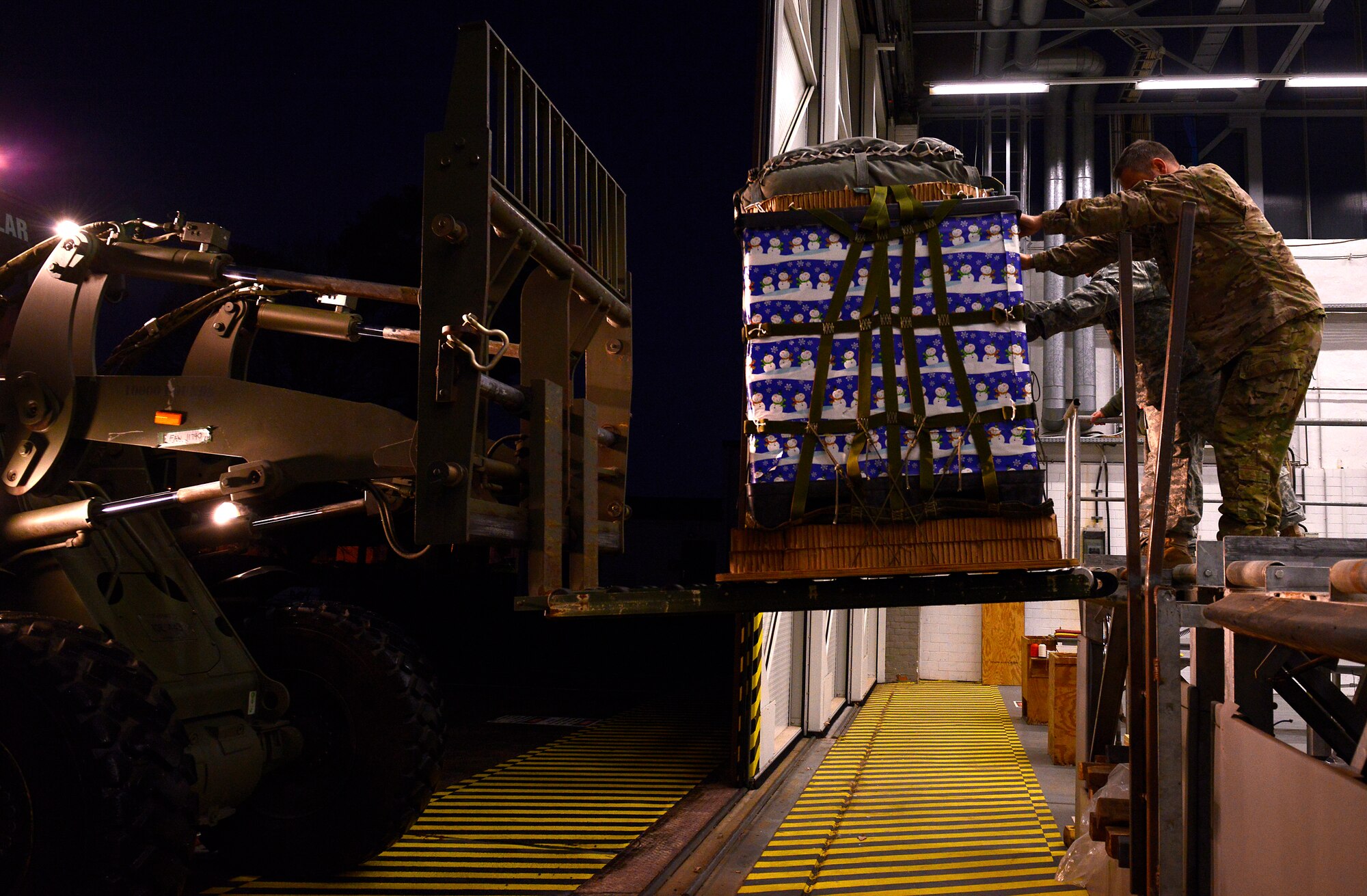Army 5th Quartermaster Detachment Soldiers load a pallet of toys onto a forklift for an International Jump Week toy drop event Dec. 7, 2015, at Ramstein Air Base, Germany. The pallet was loaded onto a C-130J Super Hercules and dropped at Alzey Drop Zone, Germany. (U.S. Air Force photo/Airman 1st Class Tryphena Mayhugh)