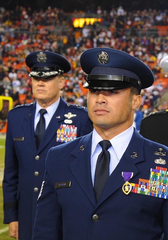 Technical Sgt. Christopher Ferrell, 11th Civil Engineer Squadron's Explosive Ordnance Disposal flight, is honored for his Purple Heart Medal by Maj. Gen. Darryl Burke, Air Force District of Washington commander, during an NFL half-time show of the Washington Redskins versus Dallas Cowboys game, Dec. 7, 2015. Ferrell was wounded while disarming a road-side bomb in Afghanistan in 2009. The ceremony was part of the Washington Redskins’ annual Salute to Service game which honors the nation's veterans and active duty military. (U.S. Air Force photo by James E. Lotz/RELEASED).
