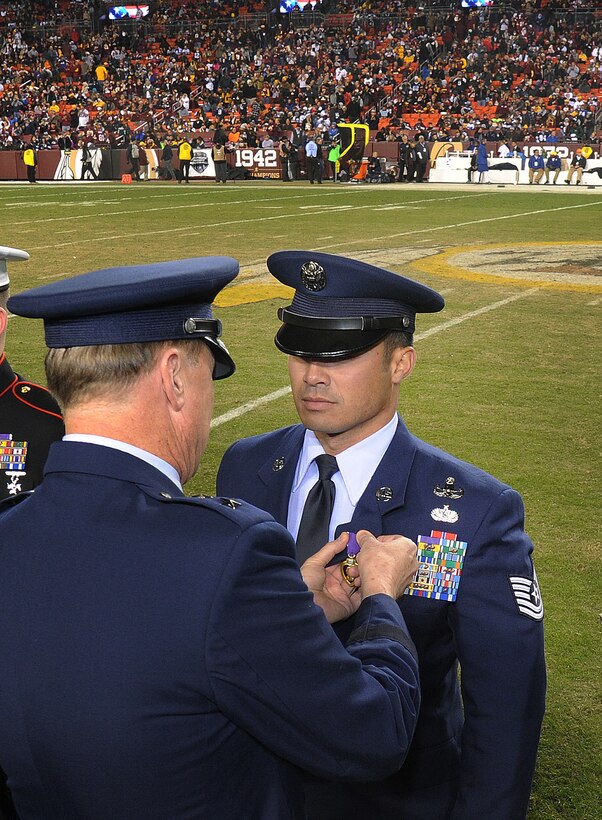 Technical Sgt. Christopher Ferrell, 11th Civil Engineer Squadron's Explosive Ordnance Disposal flight, is honored for his Purple Heart Medal by Maj. Gen. Darryl Burke, Air Force District of Washington commander, during an NFL half-time show of the Washington Redskins versus Dallas Cowboys game, Dec. 7, 2015. Ferrell was wounded while disarming a road-side bomb in Afghanistan in 2009. The ceremony was part of the Washington Redskins’ annual Salute to Service game which honors the nation's veterans and active duty military. (U.S. Air Force photo by James E. Lotz/RELEASED).