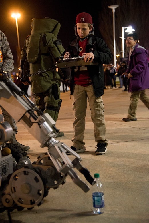A Washington Redskins fan controls an ANDROS F6A explosive ordnance disposal robot outside FedEx Field Landover, Md., Dec. 7, 2015. The 11th Civil Engineer Squadron's EOD flight displayed capabilities to the public during a Redskins Salute night with Tech. Sgt. Christopher Ferrel, a member of the 11 CES, pinning on the Purple Heart medal during halftime of the football game. (U.S. Air Force photo by Airman 1st Class Philip Bryant/Released) 
