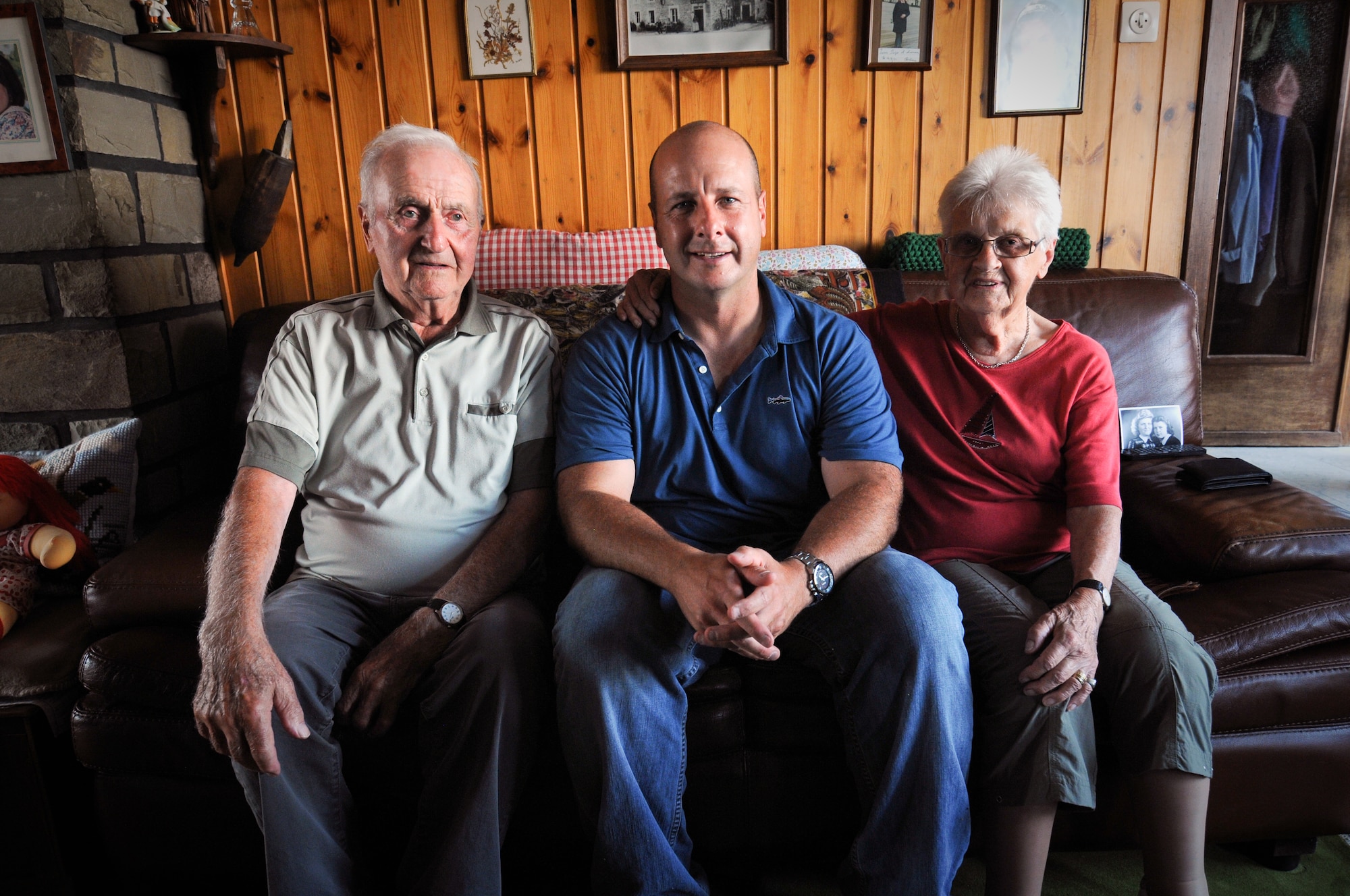 A picture of Gaston Mean, an Awyaille, Belgium, resident for more than 70 years, sits with U.S. Air Force Chief Master Sgt. James McCloskey, and Mean's wife, in the living room of the long-standing Belgian home of the Mean family.