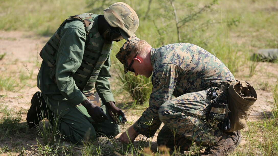 U.S. Marine Staff Sgt. Malachi McPherson, an explosive ordnance disposal technician with Special-Purpose Marine Air-Ground Task Force Crisis Response-Africa, assists a Uganda People’s Defense Force soldier during a demolition range at Camp Singo, Uganda, Dec. 7, 2015. The demolition range was conducted to develop a better understanding of types of explosives and their capabilities for UPDF soldiers who may be responsible for eliminating improvised explosive device threats or obstacles for convoys in their African Union mission in Somalia. 