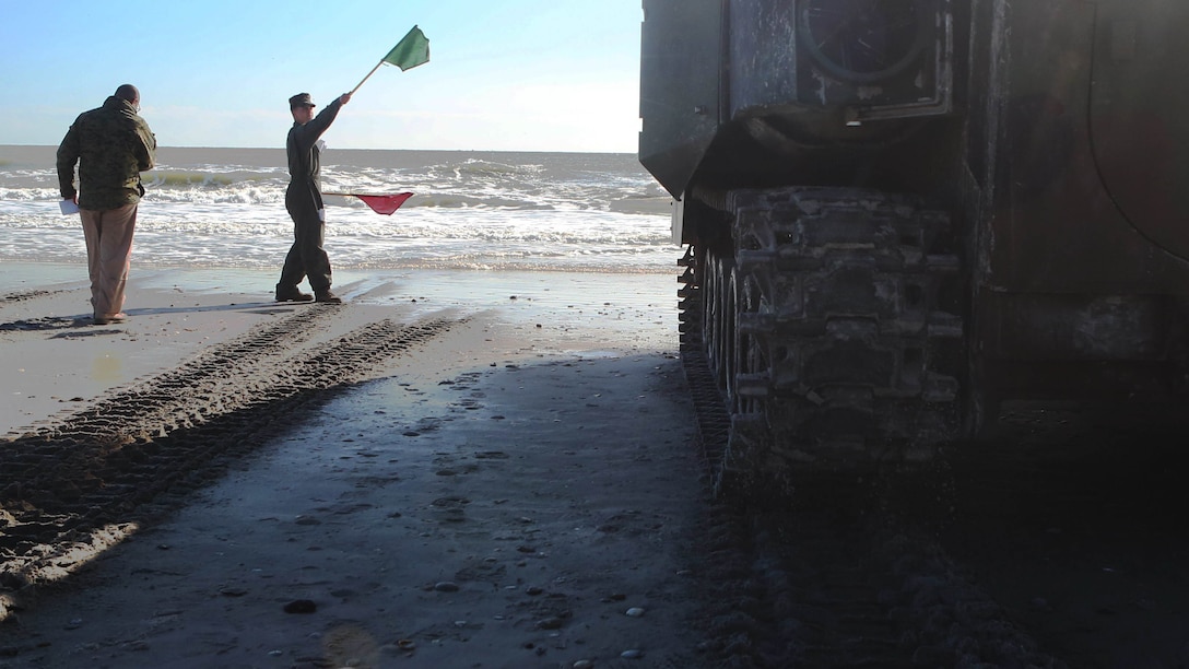 A Marine with Alpha Company, 2nd Assault Amphibian Battalion, gives the signal to an amphibious assault vehicle as the unit prepares to conduct company-level beach operations on Marine Corps Base Camp Lejeune, N.C., Dec. 5, 2015. During this exercise the unit conducted maneuvers simulating a mechanized infantry company in preparation for upcoming operations.