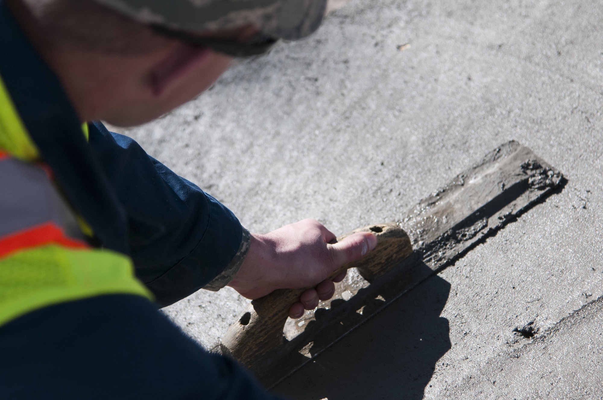 Staff Sgt. Justin Morrison, 90th Civil Engineer Squadron Pavements and Equipment, smooth’s out concrete poured outside the Chadwell Dining Facility on F.E. Warren Air Force Base, Wyo., Nov. 10, 2015. The concrete replaced gravel that pedestrians often kicked into the roads, posing wear and tear issues for the road. (U.S. Air Force photo by Senior Airman Jason Wiese)
