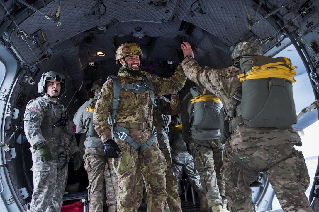 Italian jumpmaster Chief Warrant Officer 5 Marco Messina, center, high-fives U.S. Army paratroopers as they board a C-27J Spartan aircraft during the 18th Annual Randy Oler Memorial Operation Toy Drop on Camp Mackall, N.C., Dec. 7, 2015. U.S. Air Force photo by Staff Sgt. Douglas Ellis