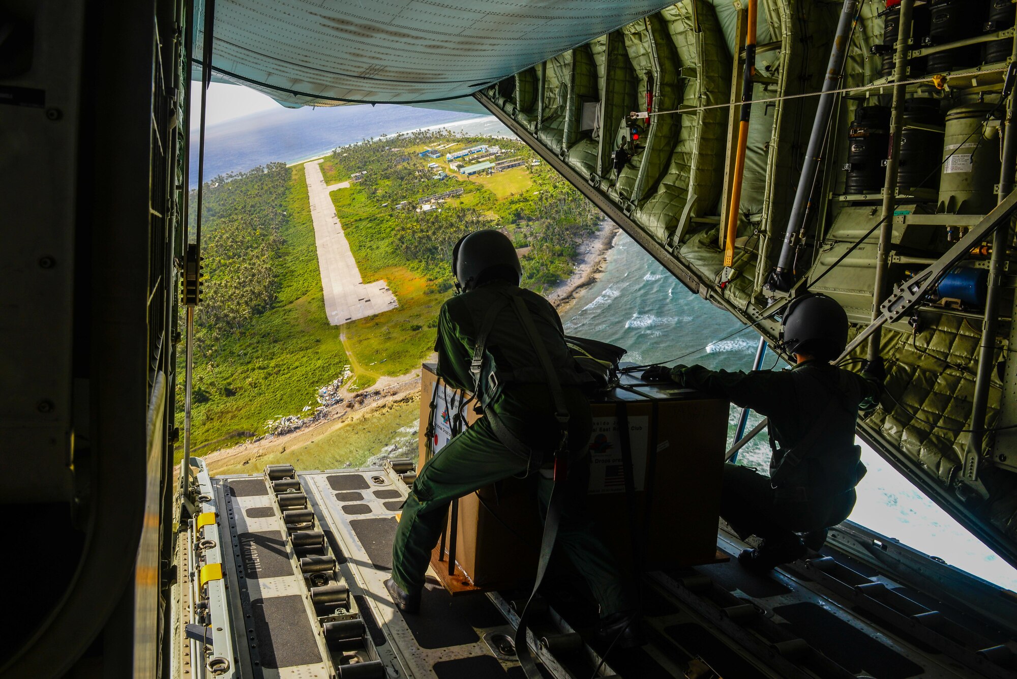 Japanese Air Self-Defense Force Master Sgt. Toyonaga Toshihisa, left, and Tech. Sgt. Takahashi Tetsuki’s, both 1st Tactical Airlift Wing loadmasters,  look over the landing zone on the remote Micronesian island of Asor from the back of a C-130 Hercules Dec. 8, 2015, during Operation Christmas Drop. The 2015 Christmas Drop missions mark the first time the event includes trilateral air support from the JASDF and Royal Australian Air Force. (U.S. Air Force photo/Staff Sgt. Alexander Riedel)