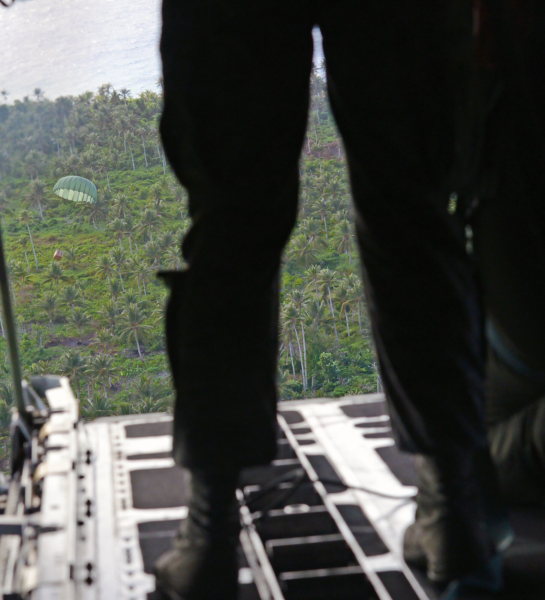 Loadmasters from the 36th Airlift Squadron, Yokota Air Base, watch a low-cost low-altitude bundle filled with donated goods and supplies drop onto the island of Fais from the back of a C-130H during Operation Christmas Drop, Dec. 8, 2015. This is the first trilateral Operation Christmas Drop where the U.S. Air Force, Japan Air Self-Defense Force and the Royal Australian Air Force work together to provide critical supplies to 56 Micronesian islands impacting 20,000 islanders covering 1,000 by 1,800 nautical miles. (U.S. Air Force photo by Tech. Sgt. Melissa K. Mekpongsatorn)