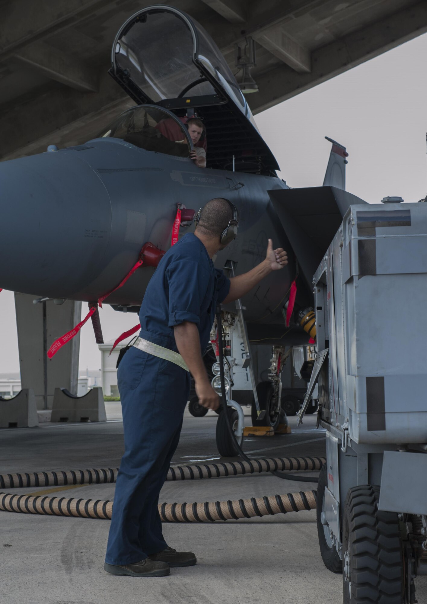 U.S. Air Force Airman 1st Class Brandon Martel, 67th Aircraft Maintenance Unit avionics technician apprentice, signals to Senior Airman Adam Craig, 67th AMU avionics technician journeyman, that the power cart, used to supply power to the F15C Eagle during maintenance, is operating correctly, Dec. 8, 2015, at Kadena Air Base, Japan. Teamwork is a vital part of the operational checks the 67th AMU completes daily. (U.S. Air Force photo by Airman Zackary A. Henry)