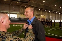 Maj. Christopher Buck, left, Recruiting Station Lansing commanding officer, pins the Purple Heart medal on the collar of Darren D. Minder, a former Marine Corps sergeant, inside the Saginaw Valley State University Field House, Dec. 5, 2015. Darren received the Purple Heart for sustaining an enemy gunshot wound to the abdomen while on a patrol during his deployment to Habbinyah, Iraq, as a corporal on Oct. 4, 2006.