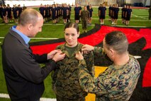 Leah J. Minder, middle, a Marine Corps recruiter in Mt. Pleasant, Mich., receives a promotion to staff sergeant inside the Saginaw Valley State University Field House, Dec. 5, 2015. Minder’s rank is pinned to her collars by 1stSgt Todd Braun, right, Alpha Company I-I, 1st battalion 24th Marines, 25th regiment, 4th Marine Division, first sergeant in Grand Rapids, Mich., and her husband, Darren D. Minder, left, former Marine Corps sergeant and Purple Heart medal recipient. 