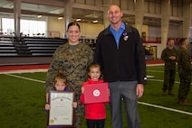 Staff Sgt. Leah J. Minder, left, a Marine recruiter in Mt. Pleasant, Mich., and her husband, Darren D. Minder, right, former Marine Corps sergeant and Purple Heart recipient, stand with their daughters, Jordan, left, and Addison after their combined promotion and Purple Heart ceremony inside the Saginaw Valley State University Field House, Dec. 5, 2015. Staff Sergeant Minder was promoted to the rank of staff sergeant and Darren received his Purple Heart medal for sustaining an enemy gunshot wound to the abdomen on a patrol, while deployed to Habbinyah, Iraq, as a corporal, Oct. 4, 2006. 