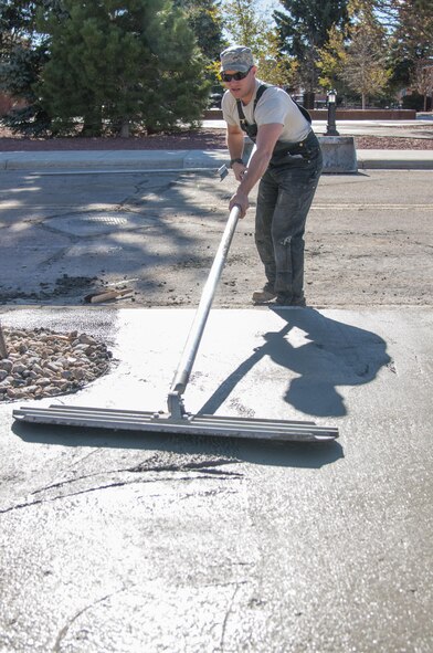 Tech. Sgt. Mike Rich, 90th Civil Engineer Squadron Pavements and Equipment, uses a bull float to smooth out large sections of newly poured concrete outside the Chadwell Dining Facility on F.E. Warren Air Force Base, Wyo., Nov. 10, 2015. 90th CES Airmen complete a wide range of maintenance and construction projects each year. (U.S. Air Force photo by Senior Airman Jason Wiese)