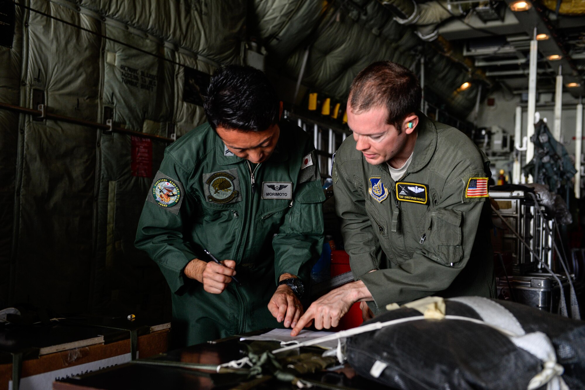 Japanese Air Self-Defense Force Tech. Sgt. Satoshi Marimoto, left, and U.S. Air Force Tech. Sgt. Christopher Nichols, both C-130 loadmasters, review load documents before Operation Christmas Drop flight SANTA12 Dec. 8, 2015, at Andersen Air Force Base, Guam. The 2015 Christmas Drop missions mark the first time the event includes trilateral air support from the JASDF and Royal Australian Air Force. Operation Christmas Drop is a Humanitarian Aid/Disaster Relief training event where C-130 aircrews perform low-cost, low-altitude airdrops on unsurveyed drop zones while providing critical supplies to 56 islands throughout the Commonwealth of the Northern Marianas, Federated States of Micronesia and Republic of Palau. It highlights the U.S. and allied airpower capabilities to orient and respond to activities in peacetime and crisis. (U.S. Air Force photo/Staff Sgt. Alexander W. Riedel)