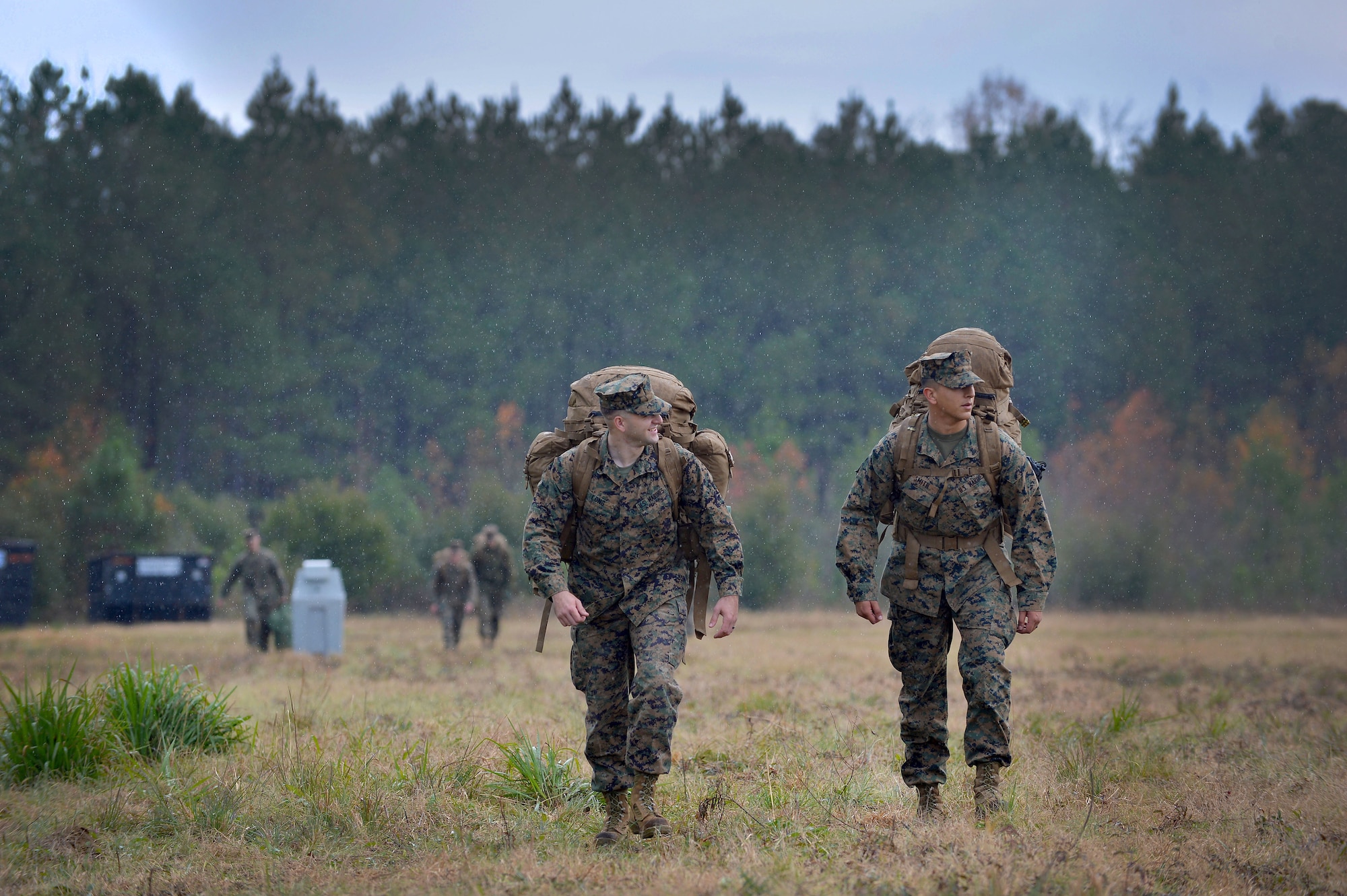 Two U.S. Marines assigned to the 273rd Marine Wing Support Squadron walk through the rain to their tents after arriving for an exercise at Poinsett Electronic Combat Range, Wedgefield, S.C., Dec. 7, 2015. The week-long exercise will test the combat capabilities of the 273rd MWSS through various operations such as crash and recovery efforts, vehicle convoys, and helicopter refueling. (U.S. Air Force photo by Senior Airman Michael Cossaboom)