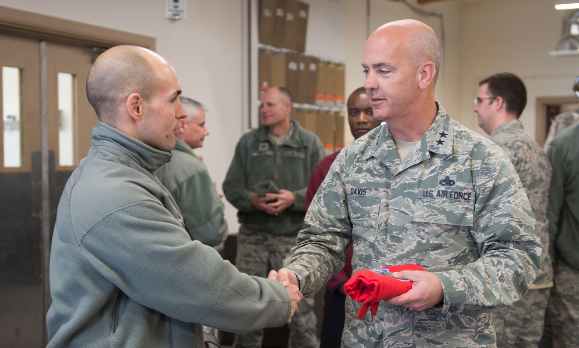 Capt. Wesley Sheppard, 366th Aircraft Maintenance Unit officer in charge, presents Maj. Gen. Glenn Davis, Air Force Life Cycle Management Center mobilization assistant to the commander, with the AMU coin and squadron t-shirt at Mountain Home Air Force Base, Idaho, Dec. 3, 2015. Davis came to see first-hand the capabilities of Mountain Home’s Strike Eagles. (U.S. Air Force photo by Senior Airman Malissa Lott/RELEASED)