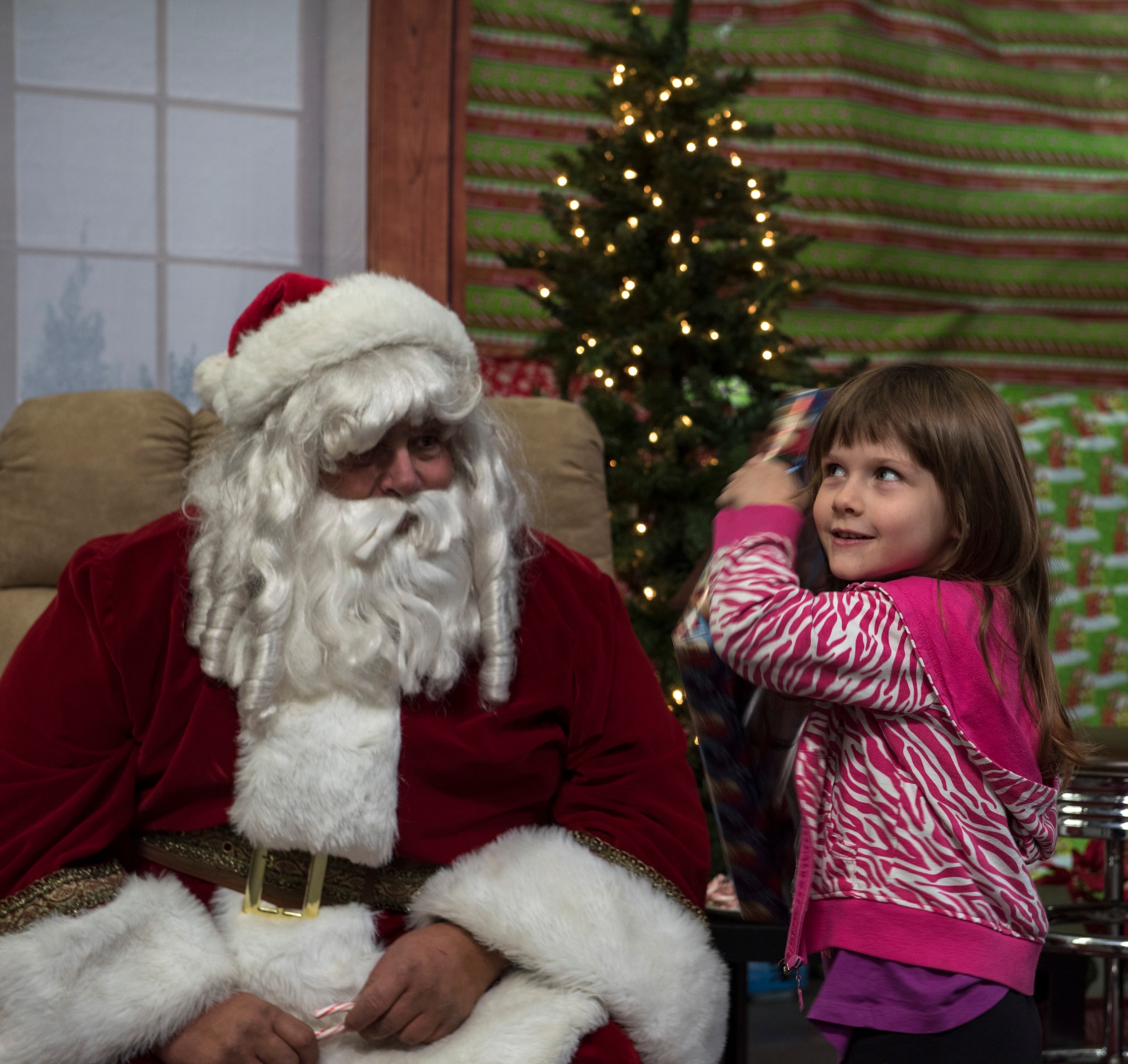 A little girl shakes a gift from Santa during Shop with a Cop, Dec. 5, 2015, in Mountain Home, Idaho. After shopping, the children were able to spend some one-on-one time with Santa and recieve a surprise gift. (U.S. Air Force photo by Airman 1st Class Connor J. Marth/Released)