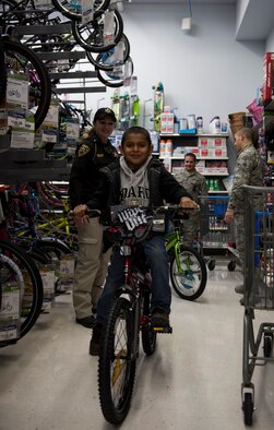A Shop with a Cop participant test rides a bike during a shopping trip, Dec. 5, 2015, in Mountain Home, Idaho. For many children this was the only opportunity to shop for the holidays. (U.S. Air Force photo by Airman 1st Class Connor J. Marth/Released)