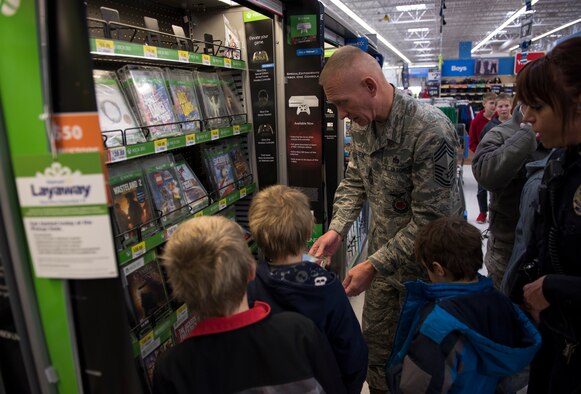 Chief Master Sgt. Richard Lien Jr., 366th Civil Engineer Squadron fire department chief, looks over different gaming options with a few of the participants of Shop with a Cop, Dec. 5, 2015, in Mountain Home, Idaho. Many of the children purchased gifts for their families during the event. (U.S. Air Force photo by Airman 1st Class Connor J. Marth/Released)