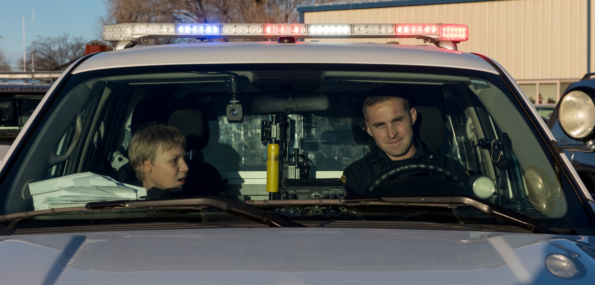 A local officer from the community and a Shop with a Cop participant prepare to convoy from the Elk Lodge to a shopping center in Mountain Home, Idaho, Dec. 5, 2015. Before taking off from the Elk Lodge, law enforcement officers gave the children a chance to check out the vehicles. (U.S. Air Force photo by Airman 1st Class Connor J. Marth/Released)