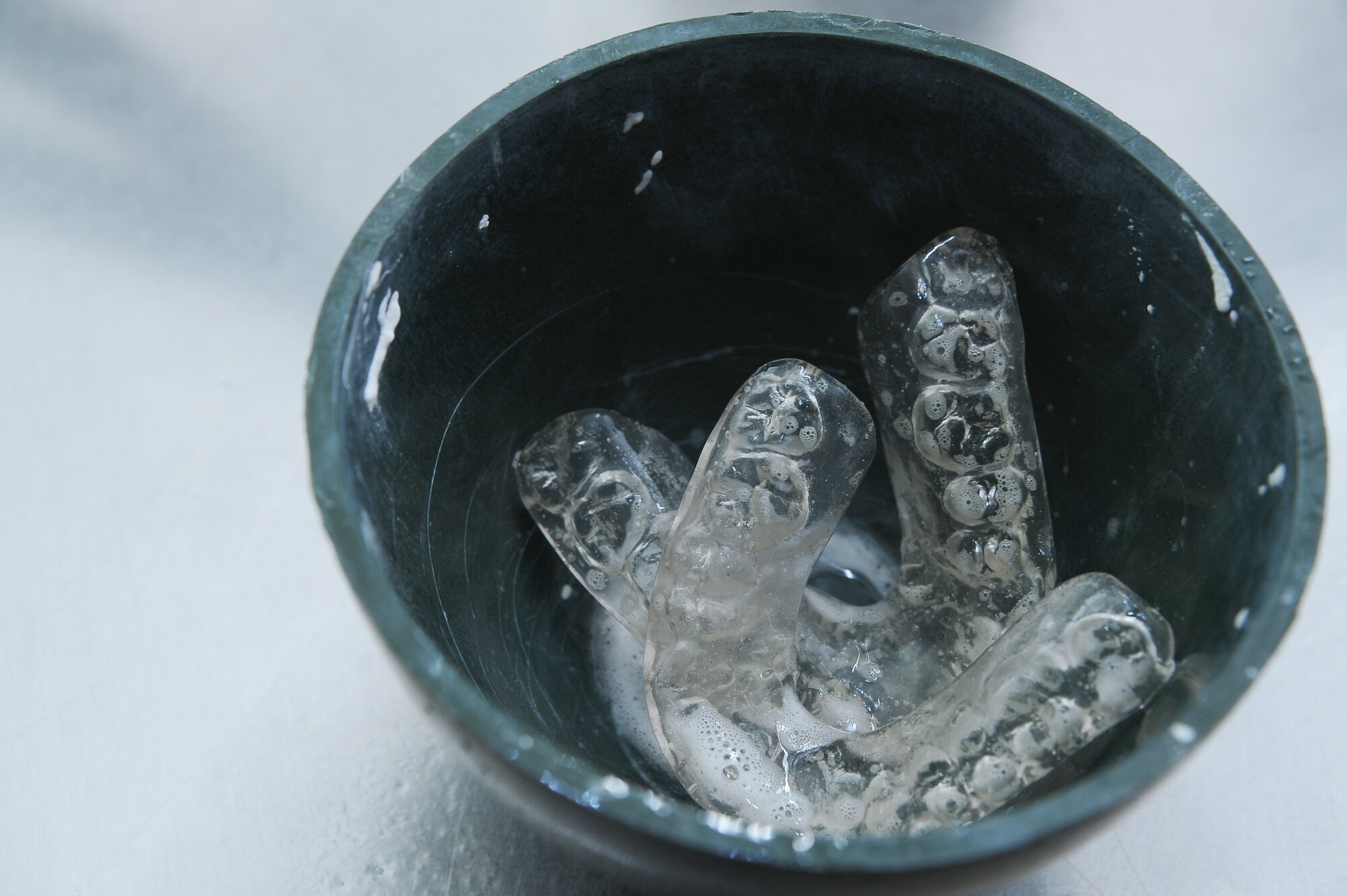 A set of plastic teeth retainers soaks in disinfectant in the 355th Dental Squadron laboratory at Davis-Monthan Air Force Base, Ariz., Nov. 3, 2015. 355th Dental Squadron laboratory technicians rinse the retainers with disinfectant before dentists deliver to patients. (U.S. Air Force photo by Airman 1st Class Mya M. Crosby/Released)