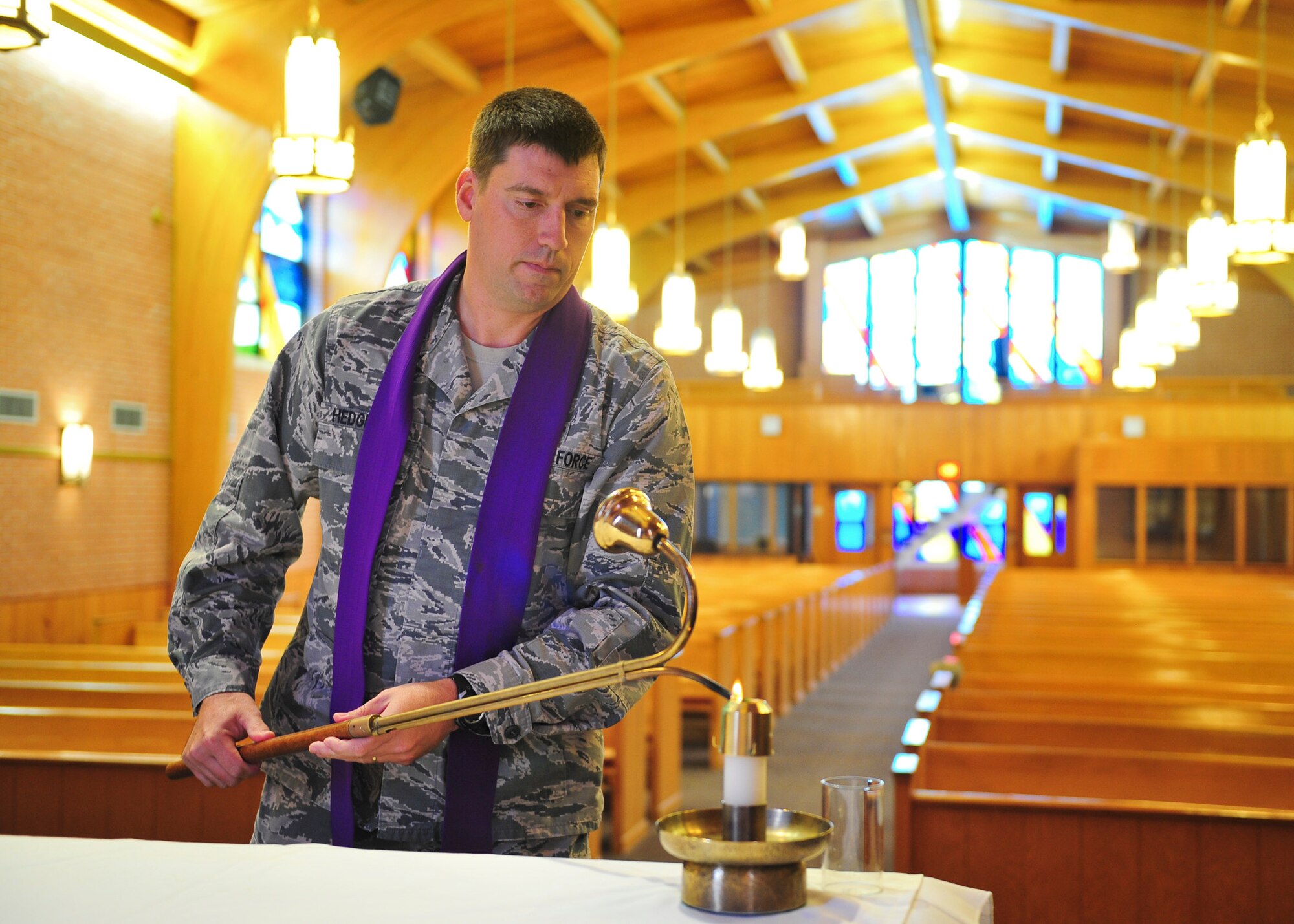 Captain Brett Hedgepeth, a chaplain with the 325th Fighter Wing, lights a candle Dec. 2. in Chapel 2. The Chaplain Corps provides spiritual care and is in place to protect and defend all Airmen and their family's constitutional right to free exercise of religion. (U.S. Air Force photo by Senior Airman Dustin Mullen/Released)