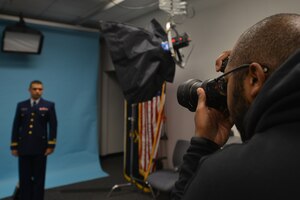 Christopher Thompson, a photographer with the Joint Base Langley-Eustis Enterprise Multimedia Center, takes an official photo of U.S. Coast Guard Lt. Jr. Jose Raflos, an EMC customer, at Fort Eustis, Va., Dec. 1, 2015. The center provides photography support including official photos, event photography and historical documentation. (U.S. Air Force photo by Staff Sgt. Natasha Stannard)