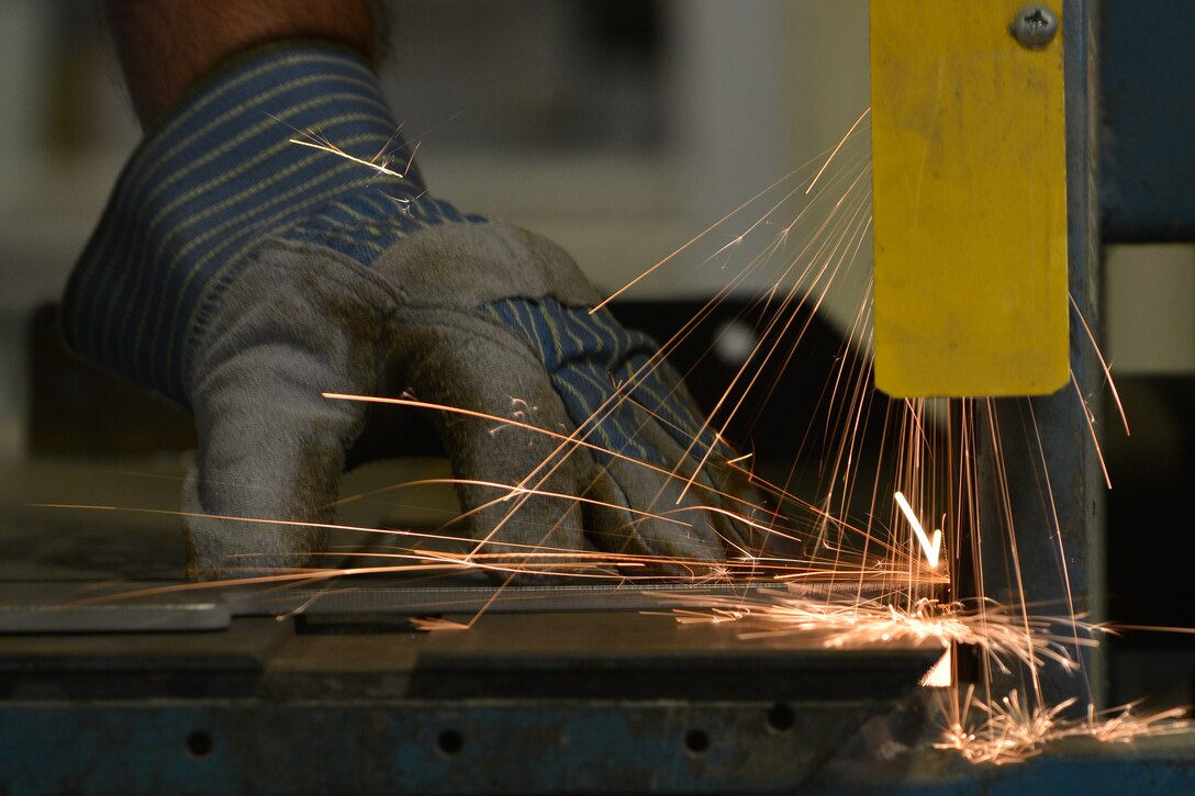 Ron Houslen, the fabrication lead with the Joint Base Langley-Eustis Enterprise Multimedia Center (EMC), shapes metal on a sander at Fort Eustis, Va., Dec. 1, 2015. The EMC’s fabrication section works with mediums ranging from metals and wood, to hardware for graphics. (U.S. Air Force photo by Staff Sgt. Natasha Stannard)
