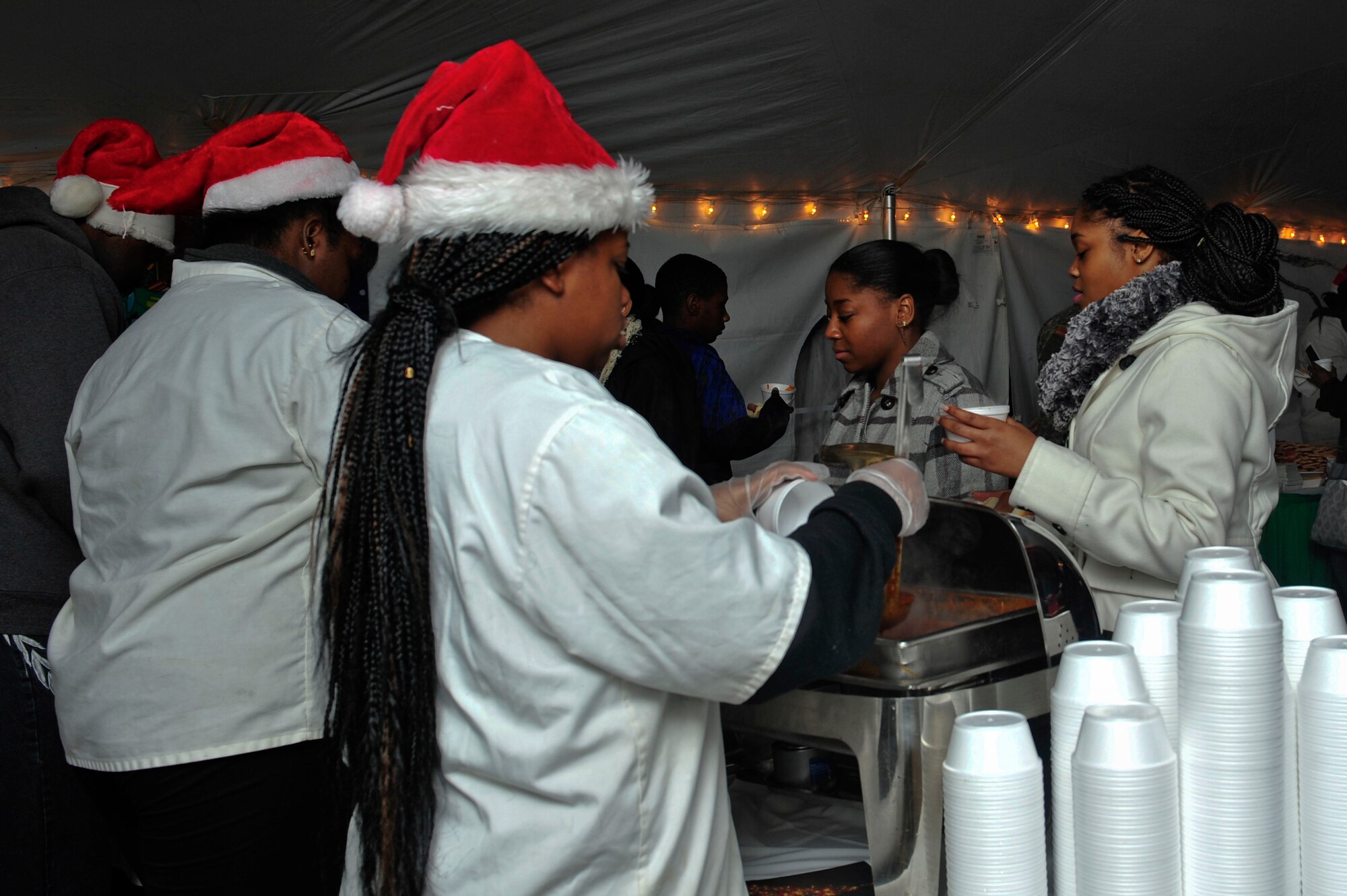 Volunteers serve chili and hot dogs to patrons of the Holiday Tree Lighting Ceremony at Seay Plaza at Fort Eustis, Va., Dec. 4, 2015. The ceremony also featured holiday songs played by the U.S. Army Training and Doctrine Command band. (U.S. Air Force photo by Senior Airman Breonna Veal)