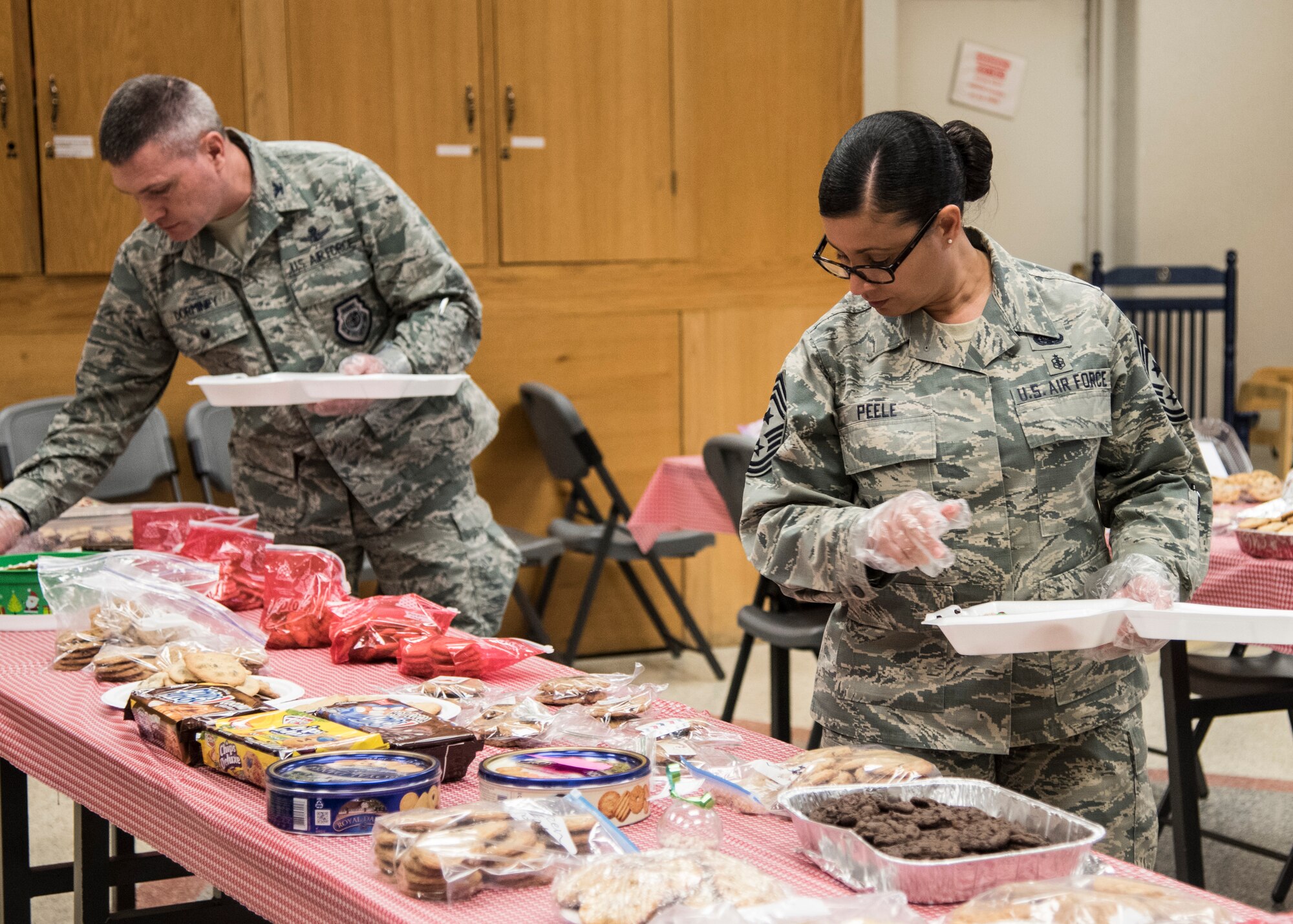 PETERSON AIR FORCE BASE, Colo. – Col. Eric Dorminey, 21st Space Wing vice commander, and Chief Master Sgt. Idalia Peele, 21st Space Wing command chief, package baked desserts during the “Cookies for the Troops” event at the Peterson Chapel, Dec. 8, 2015. Hosted by the Peterson, Schriever, Cheyenne Mountain Spouses’ Club, the cookie drive collects cookies for dorm residents and those on shift work during the holiday season. (U.S. Air Force photo by Senior Airman Tiffany DeNault)