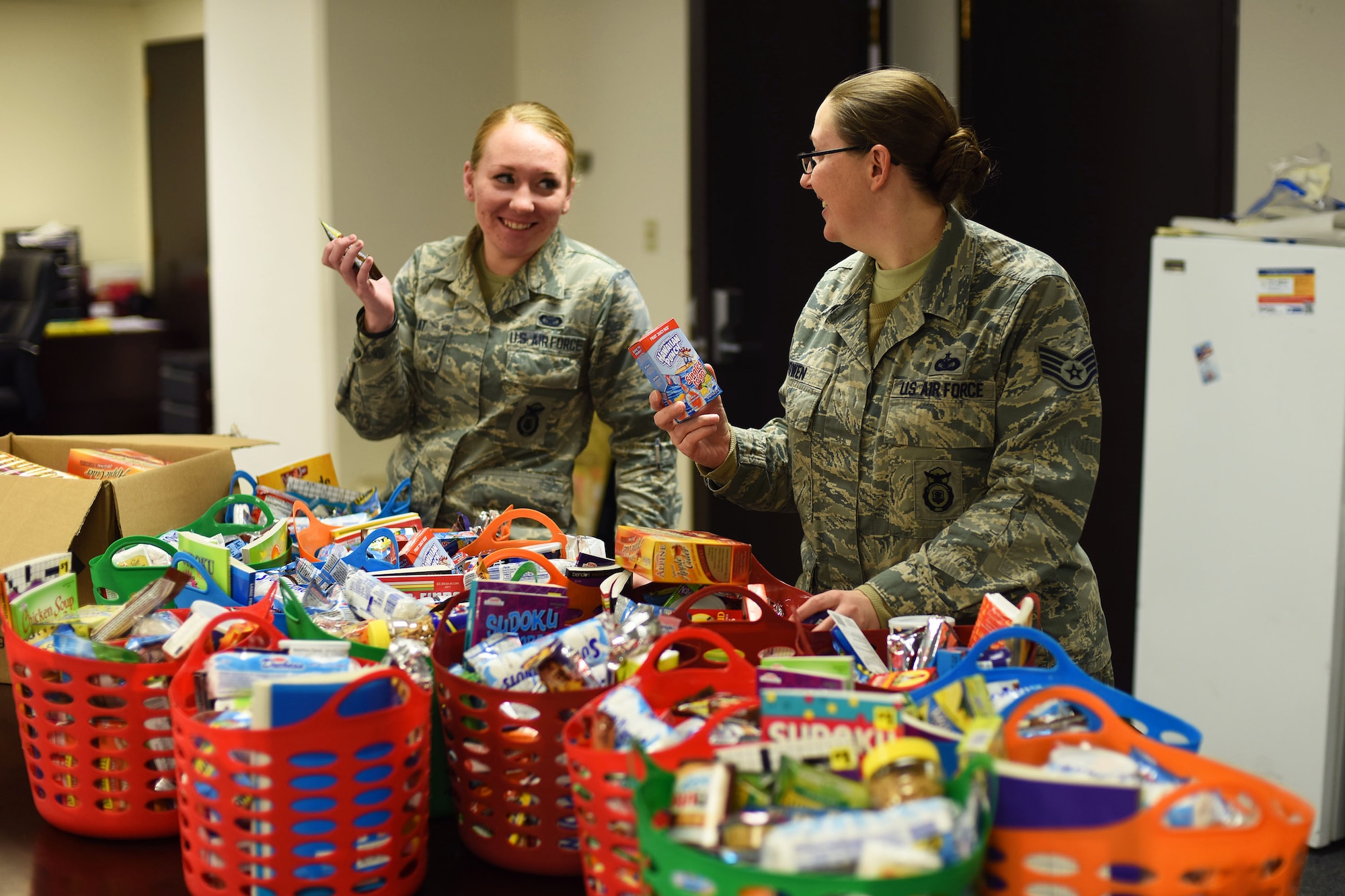 Airman 1st Class Kelsey Pilat, 741st Missile Security Forces Squadron support team leader, left, jokes with her supervisor Staff Sgt. Elizabeth Bowen, 741st MSFS operations support, as they organize care packages Dec. 8, 2015 before sending them to missile alert facilities near Malmstrom Air Force Base, Mont. More than 1,000 items were donated in support of Airmen who locally deploy to the missile field during the holiday season. (U.S. Air Force photo/Airman Collin Schmidt) 