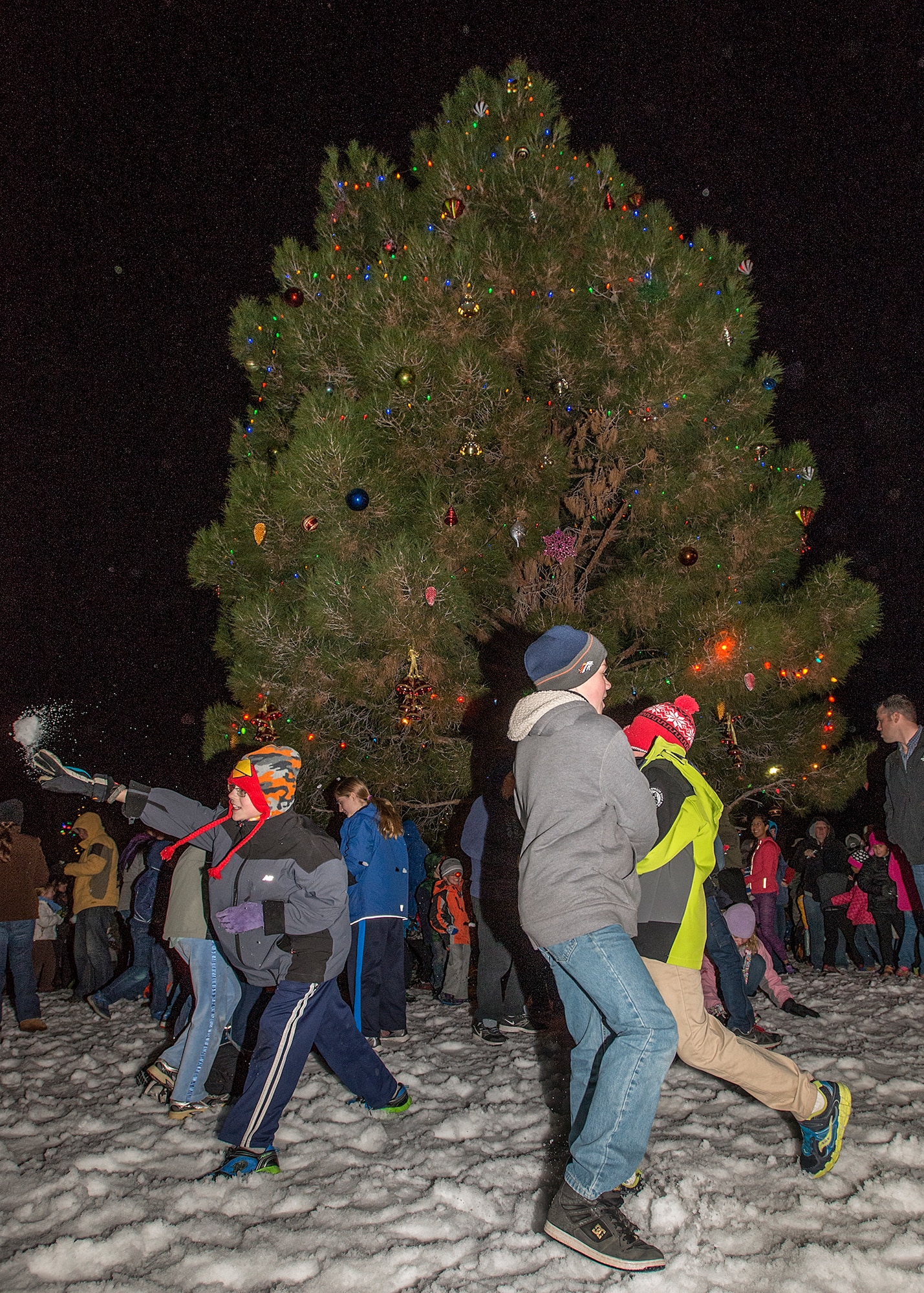 Children play in the fake snow surrounding the Edwards community Christmas tree following the Edwards AFB Annual Tree Lighting Ceremony. (U.S. Air Force photo by Edward Cannon)