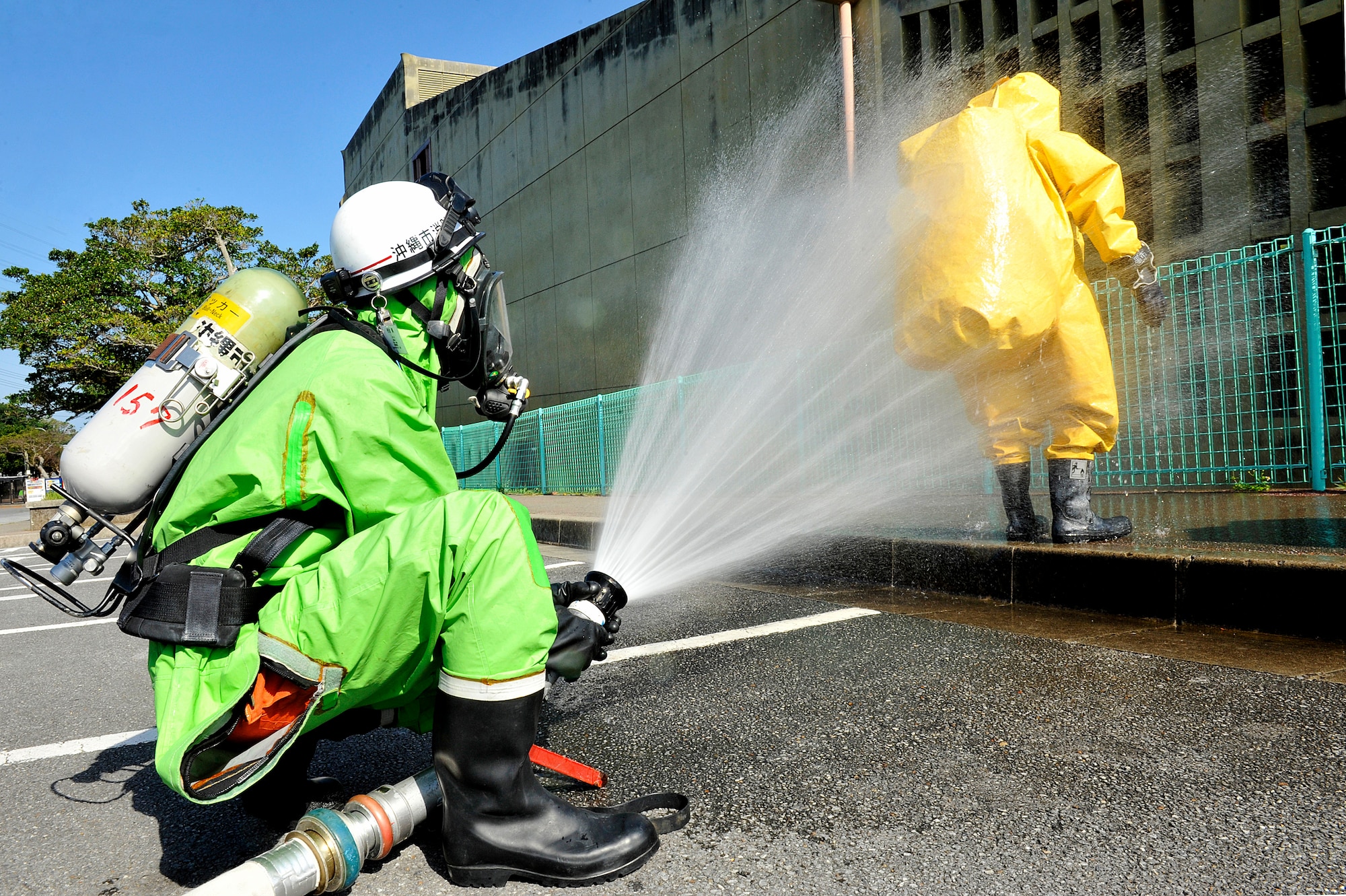 A member of the Okinawa City Fire Department rinses off a fellow firefighter before he moves through a chemical transition point during a bilateral hazardous materials training exercise, Dec. 8, 2015, at the Okinawa City Civic Center, Japan. This bilateral training exercises is intended to enhance coordination between the Kadena Air Base Fire Department and the Okinawa City Fire Department. (U.S. Air Force photo by Naoto Anazawa)